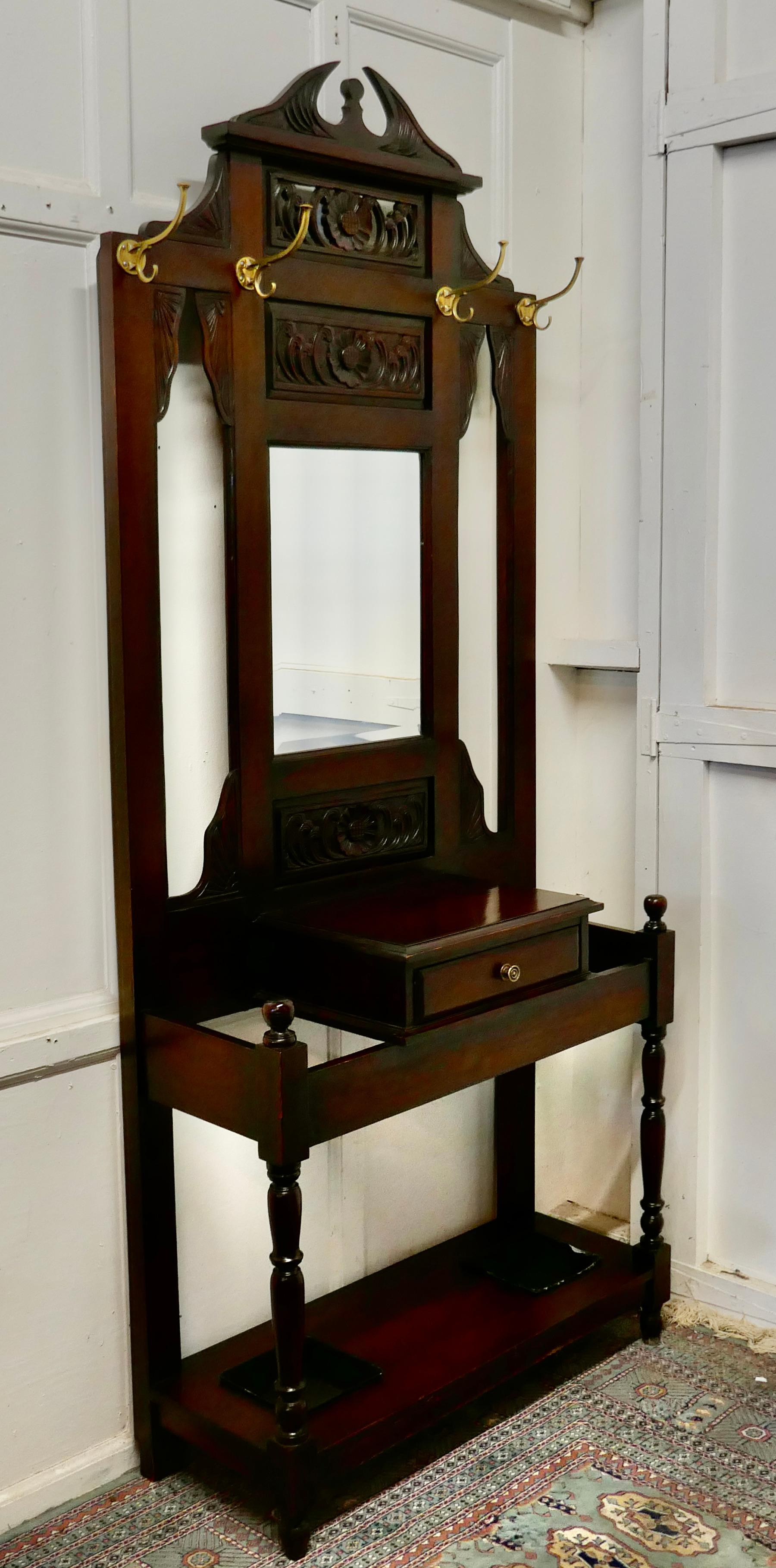 Victorian mahogany hall stand 

This is a handsome piece, the stand has an imposing Swan Neck pediment set over carved sun flowers and a central mirror.
The lower section has a lidded glove box set between the umbrella and stick stands which have