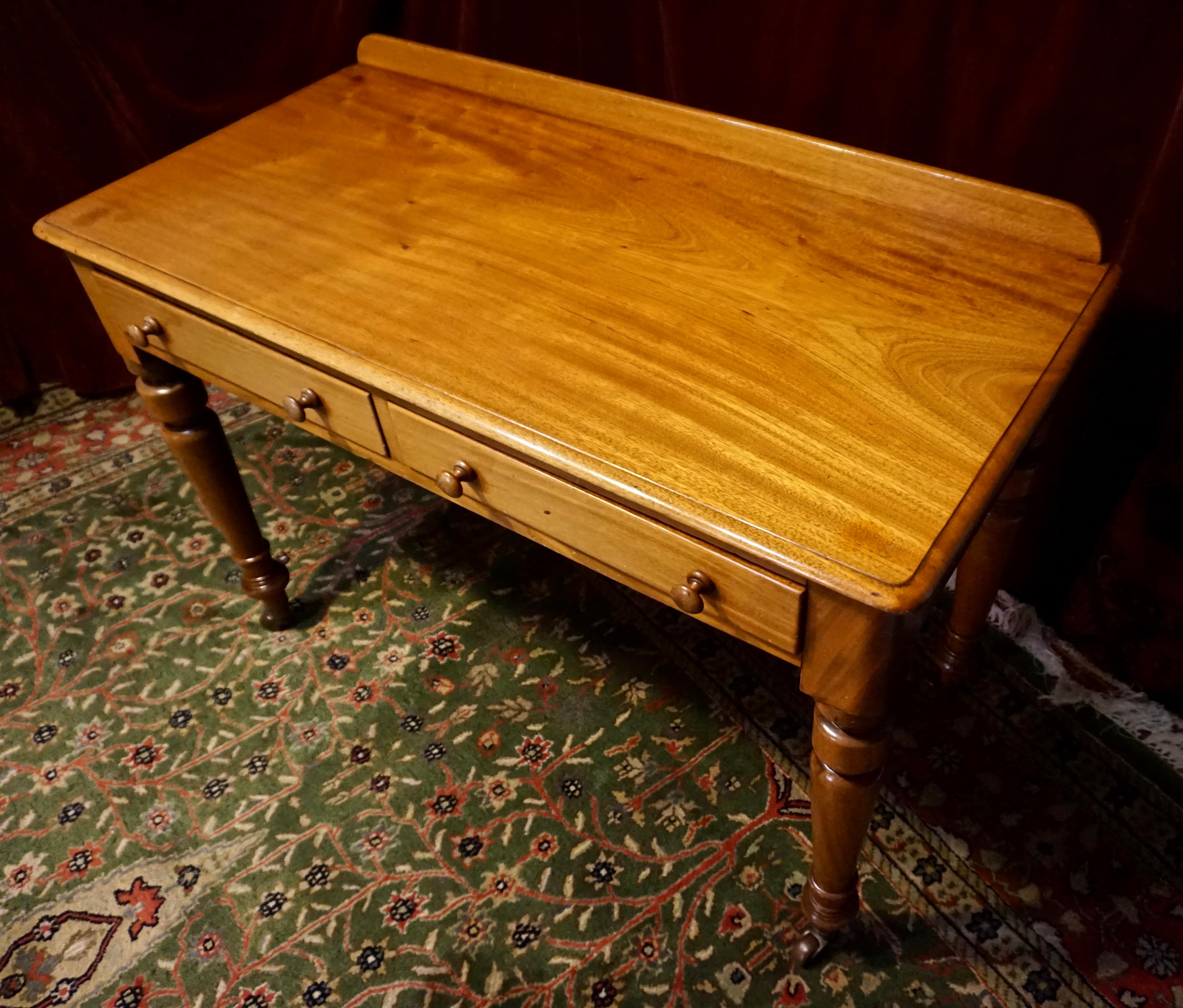 Simplicity of form and elegance shines through this beautiful Victorian writing desk; hand-crafted from old growth Mahogany. Warm, free flowing grains matched with old world craftsmanship add refinement. Porcelain casters on brass are original to it