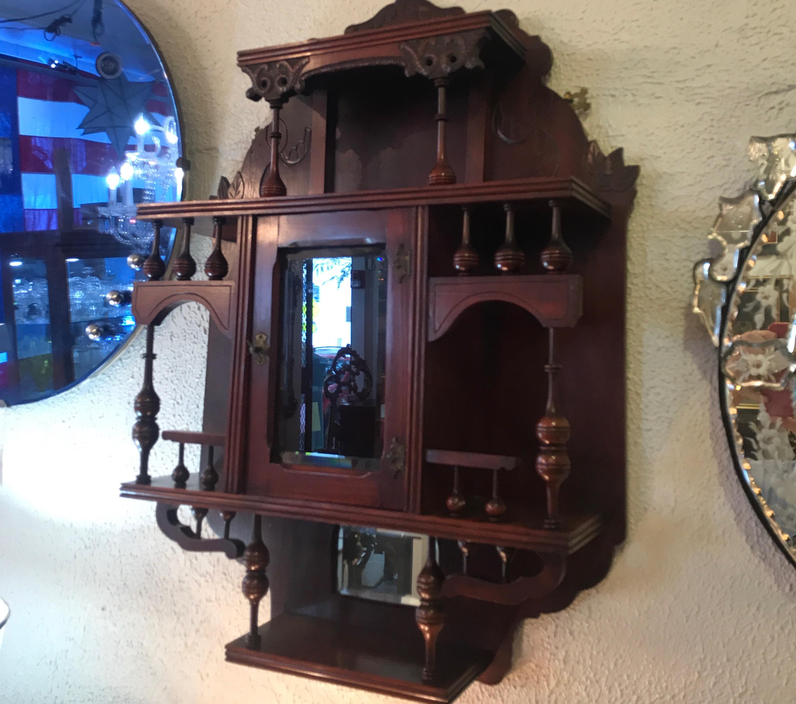 Charming mahogany hanging curio what not shelf with beveled glass and mirror. The center glass door flanked by two open shelves with display area at the top and bottom.