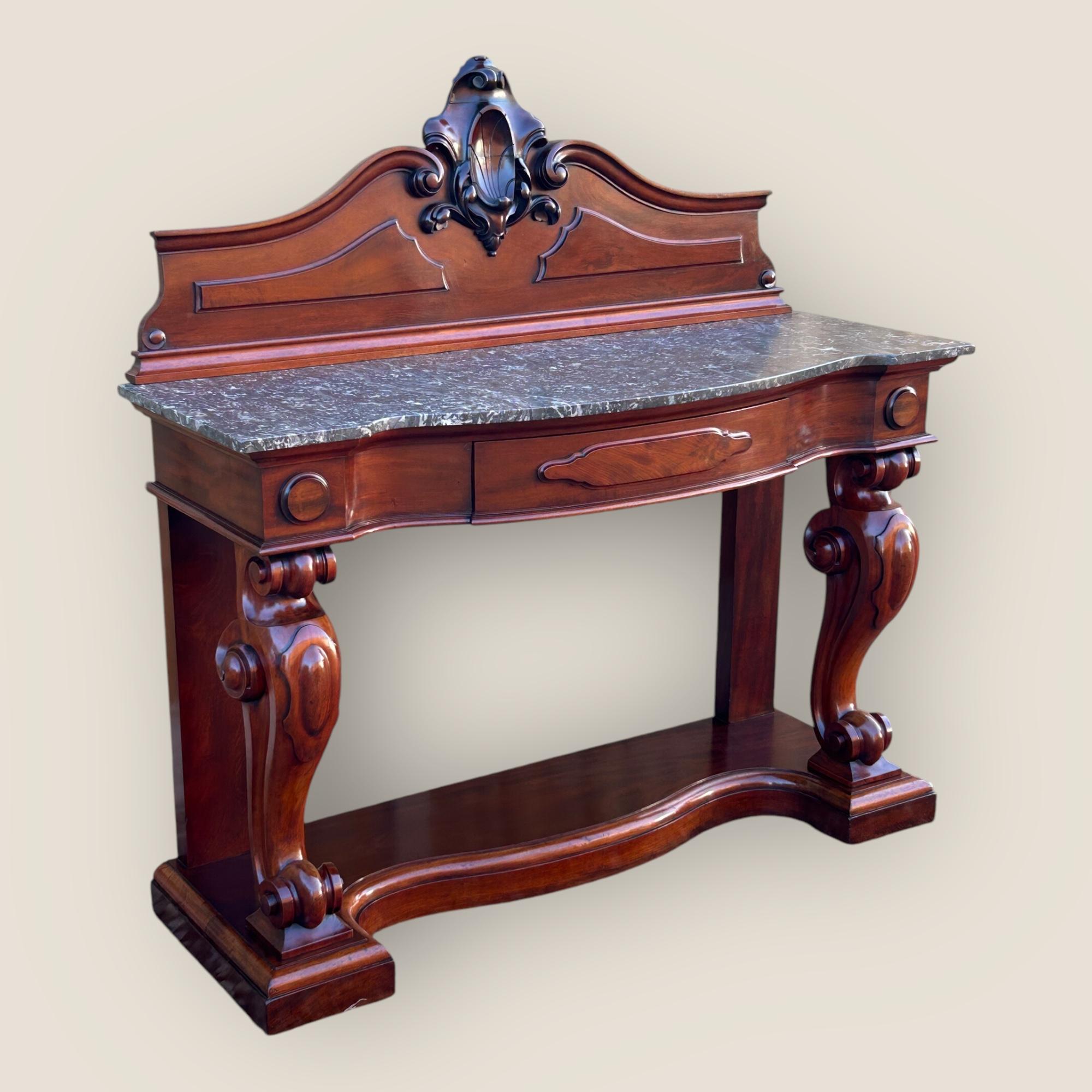 Here we have a Victorian Mahogany & Marble serpentine shaped Console Table. This console table has a shaped grey and white veined marble top, a single drawer to the centre of the frieze, a carved back to the top and moulding to the bottom of the