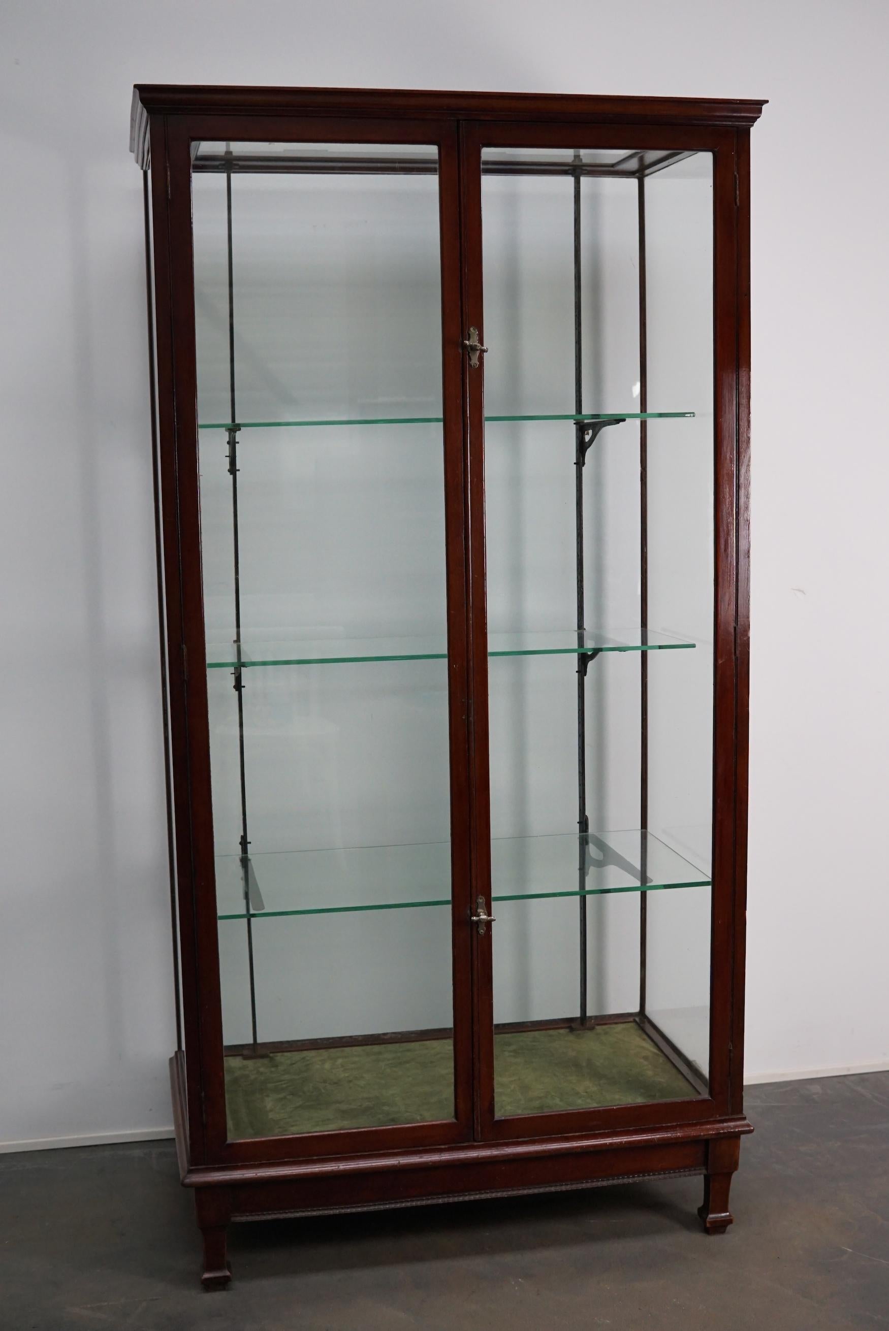 A museum quality Victorian mahogany display cabinet. This outstanding large cabinet has two glass doors fitted with original knob handles. It features three shelves on cast iron shelve holders. The floor is covered with green velvet.