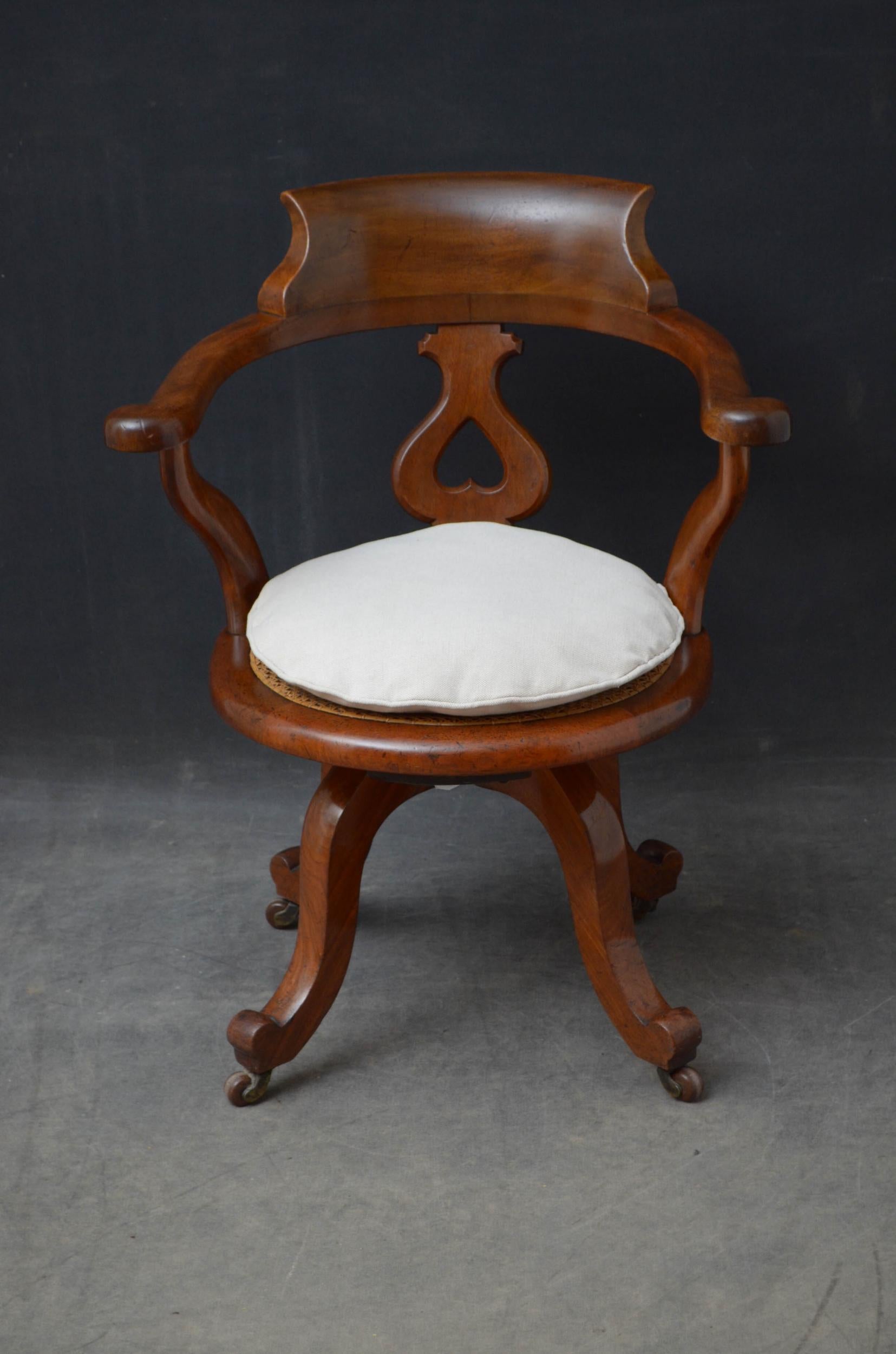 Sn5032 Victorian, mahogany, swivel desk chair, having shaped back rail with a carved splat below and a caned seat with a new cushion flanked by outswept, pad arms, all standing on cabriole legs terminating in original castors. This antique desk