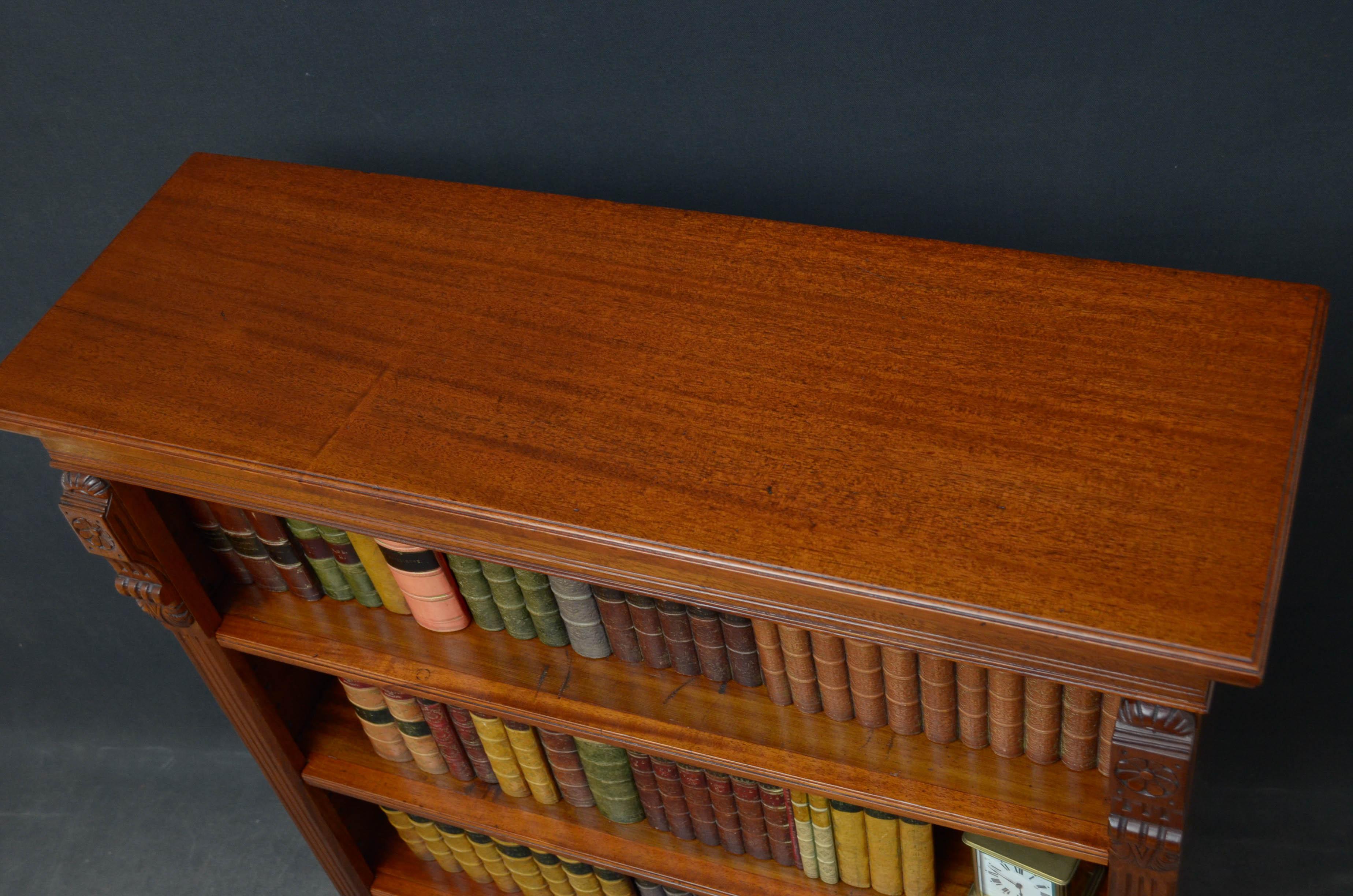 R00 late Victorian open bookcase in mahogany, having moulded top above 3 height adjustable shelves with reeded edges, flanked by drop carvings and reeded pilasters, all standing on plinth base. This antique bookcase is in home ready condition, circa