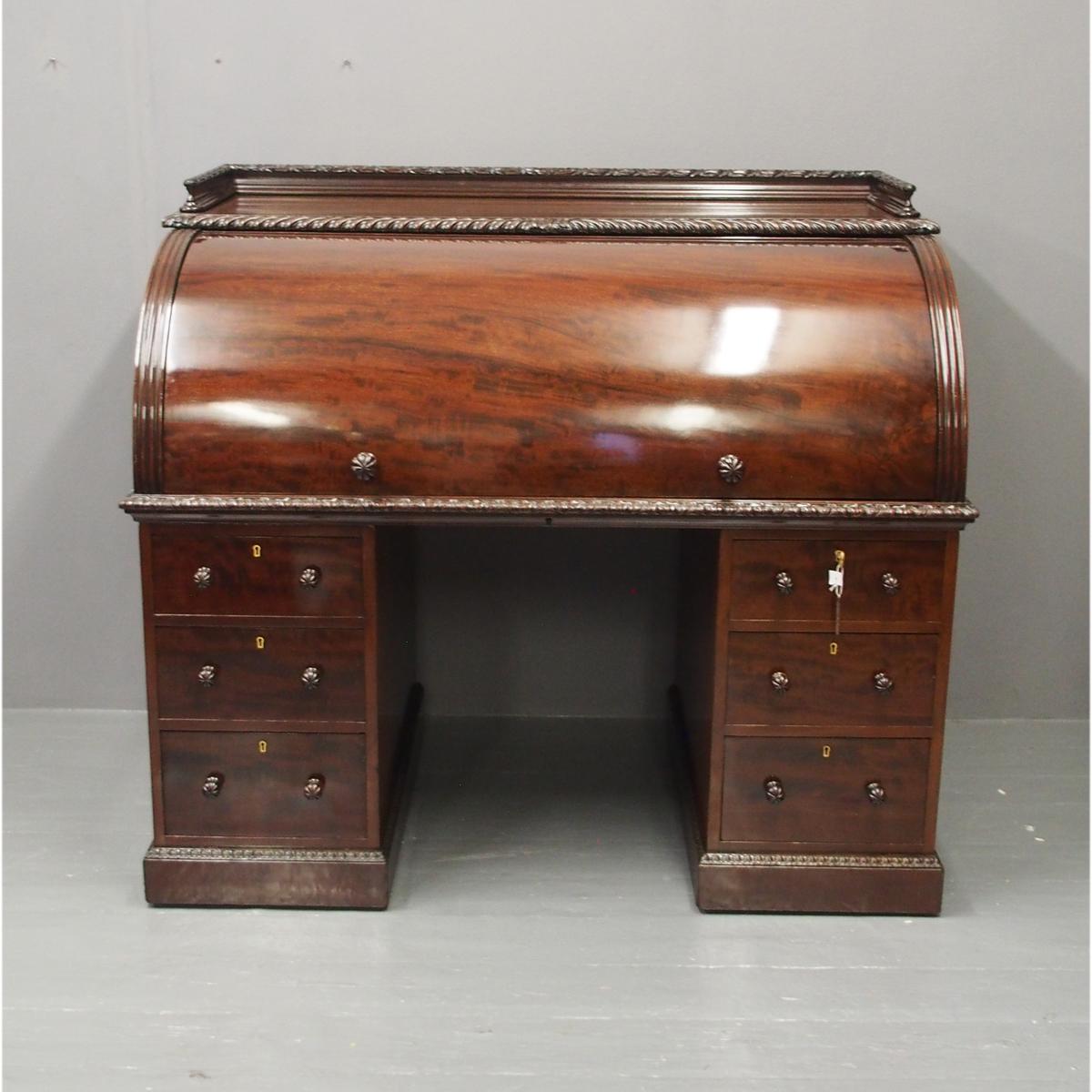 Mahogany roll top cylinder bureau, circa 1890. With a carved three quarter gallery with gadrooned fore-edge above a cylinder top opening to a configuration of pigeon holes and drawers. With a pullout / pull-out slide with tooled leather writing