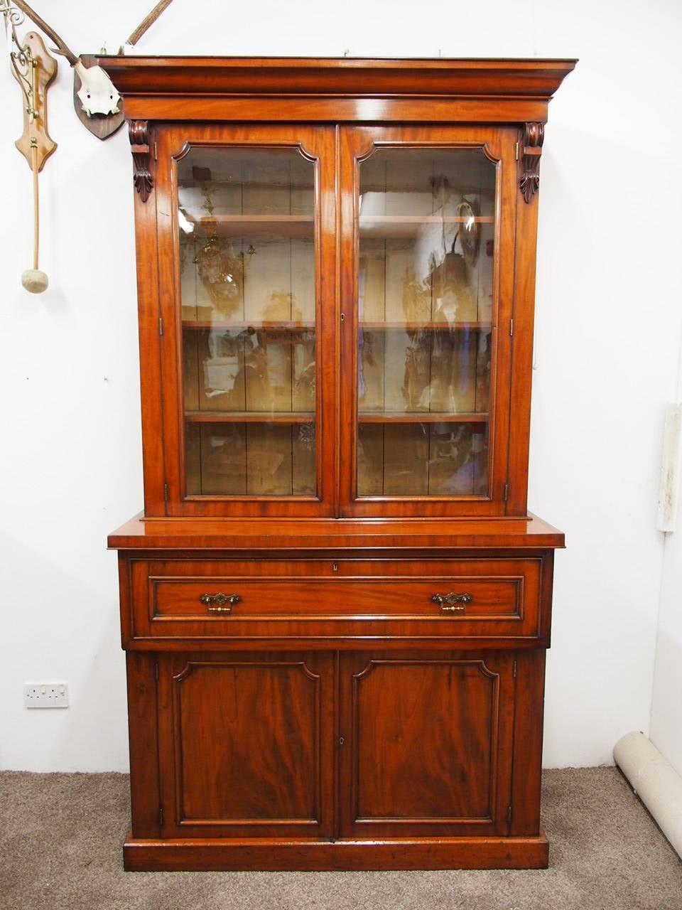 Victorian mahogany secretaire bookcase, circa 1870. With Victorian flared corners, a simple frieze and carved corbels beneath leading on to glazed doors with mahogany beading. Opening to reveal three adjustable pine shelves with mahogany facings,