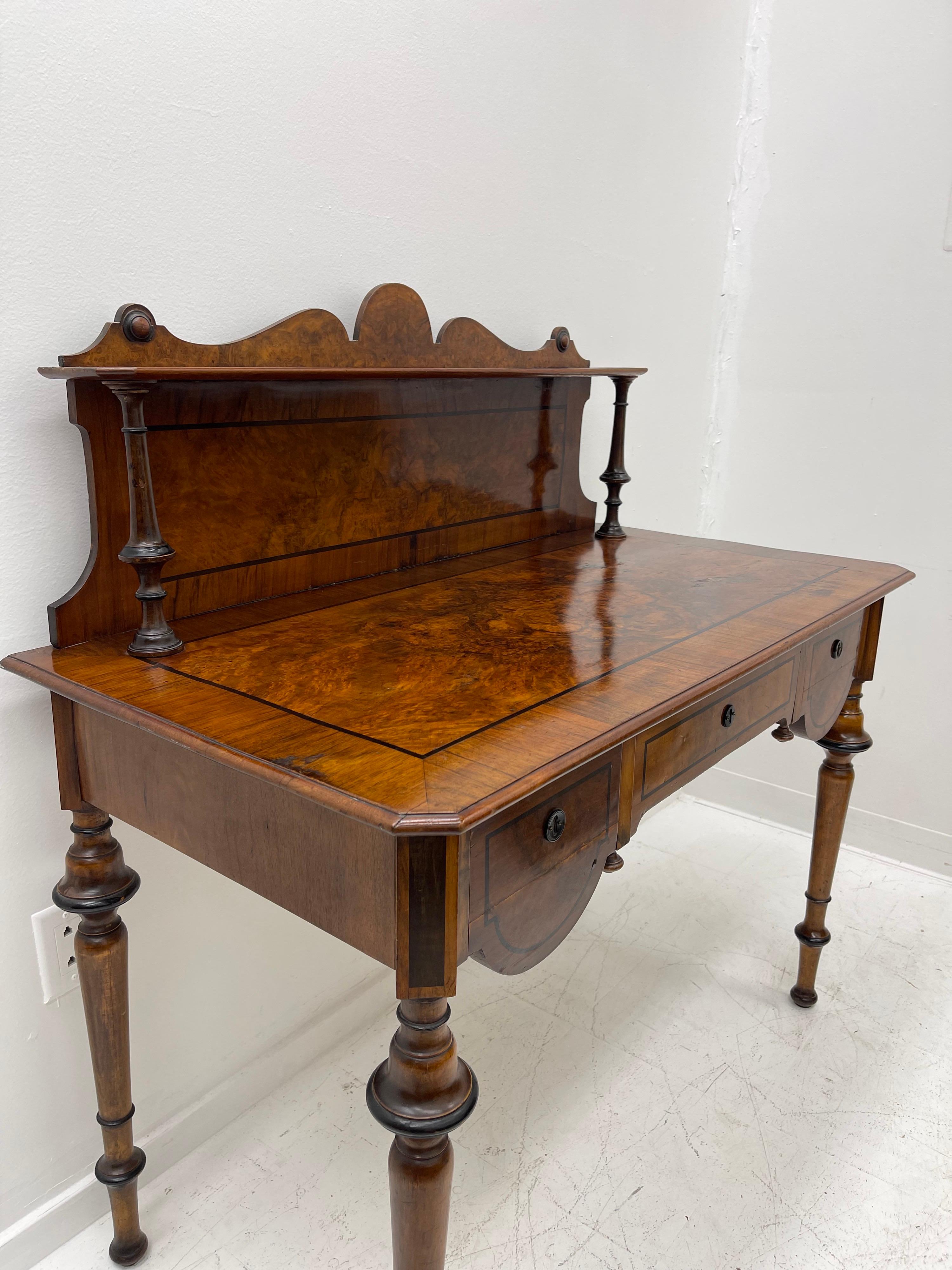 For sale is a good quality Victorian Mahogany, Satinwood Banded and Marquetry Inlaid Writing Desk. The writing surface is veneered with flame mahogany Burl panels, includes three drawers, on hand tapered legs. Overall the desk is in good original