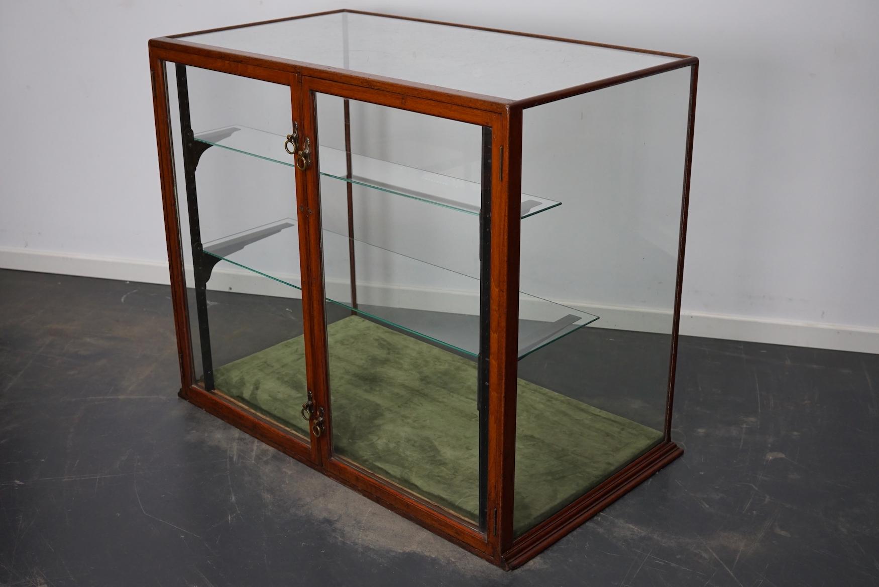 A museum quality Victorian mahogany display cabinet. This outstanding cabinet has two glass doors fitted with original knob handles. It features two shelves on cast iron shelve holders. The floor is covered with green velvet.