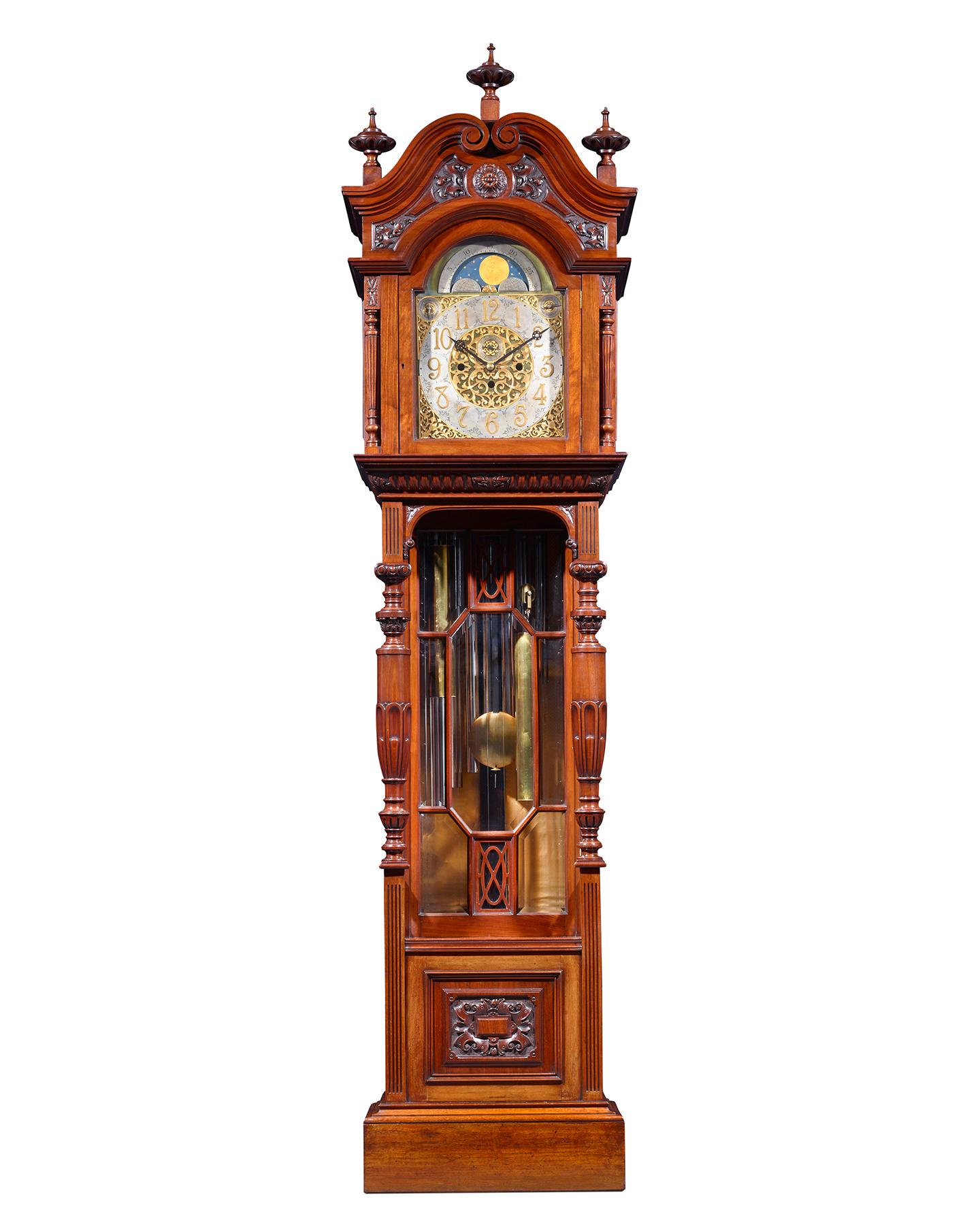 An exceptional example of Victorian clock making, this imposing tall case, or grandfather, clock towers in a masterfully carved mahogany case. A complex eight-day movement powers the clock, which features nine tubular bells inside that chime the
