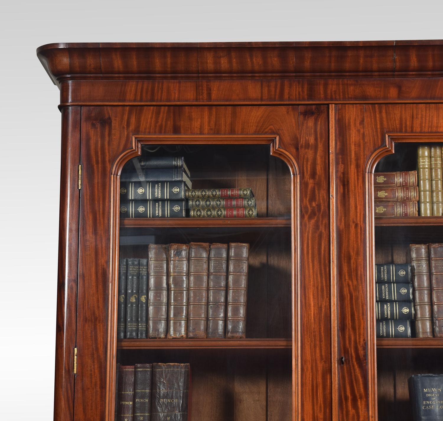 Mahogany bookcase, having ogee moulded cornice above a pair of glazed doors enclosing four adjustable shelves, the base having two short draws with carved wooden handles above two shaped figured mahogany panel fronted doors enclosing one large shelf