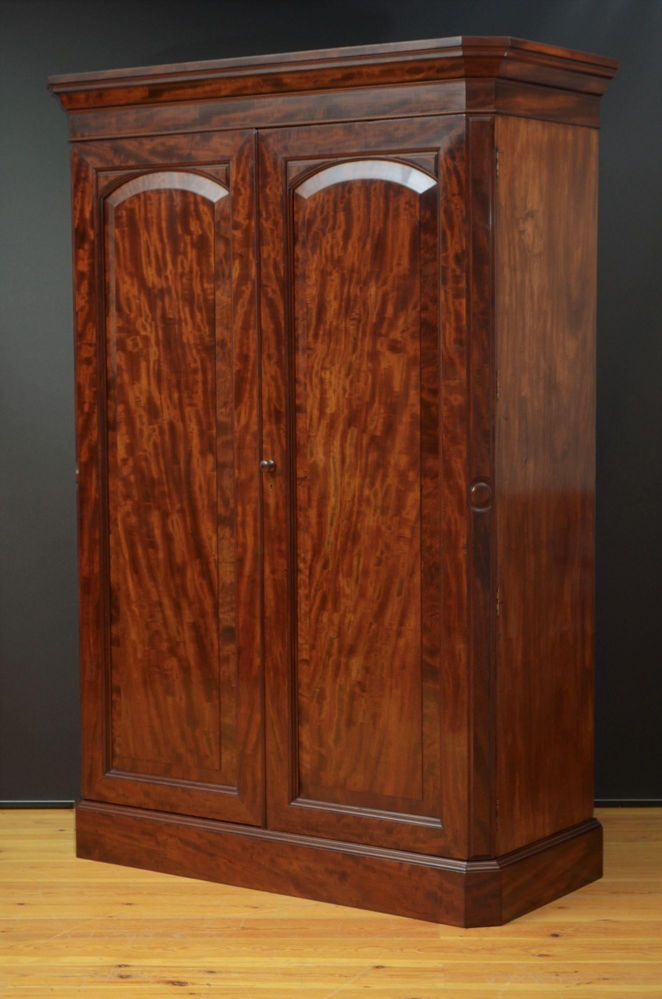 Sn5429  Fine quality and very attractive Victorian wardrobe, having cavetto cornice with canted corners above a pair of fielded and panelled figured mahogany doors with canted corners, enclosing long hanging section with a storage compartment below