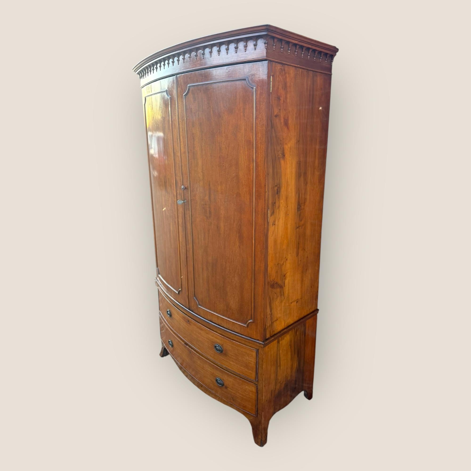 Here we have a Late Victorian, circa 1895, mahogany bow front wardrobe on splayed feet. The base has 2 drawers with a pair of brass handles on each. The 2 door middle section opens up to reveal a large hanging space with a hanging rail and coat