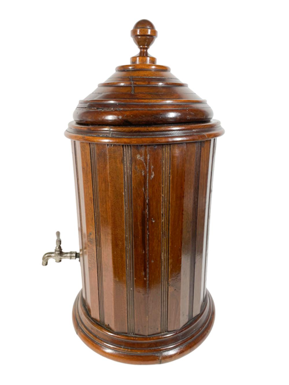 An English mahogany water / beverage cooler of cylindrical form with vertical beaded panels rising from a stepped ring foot to a stepped ring collar topped with a ring turned conical lid with ball finial. The interior fitted with an enameled cast