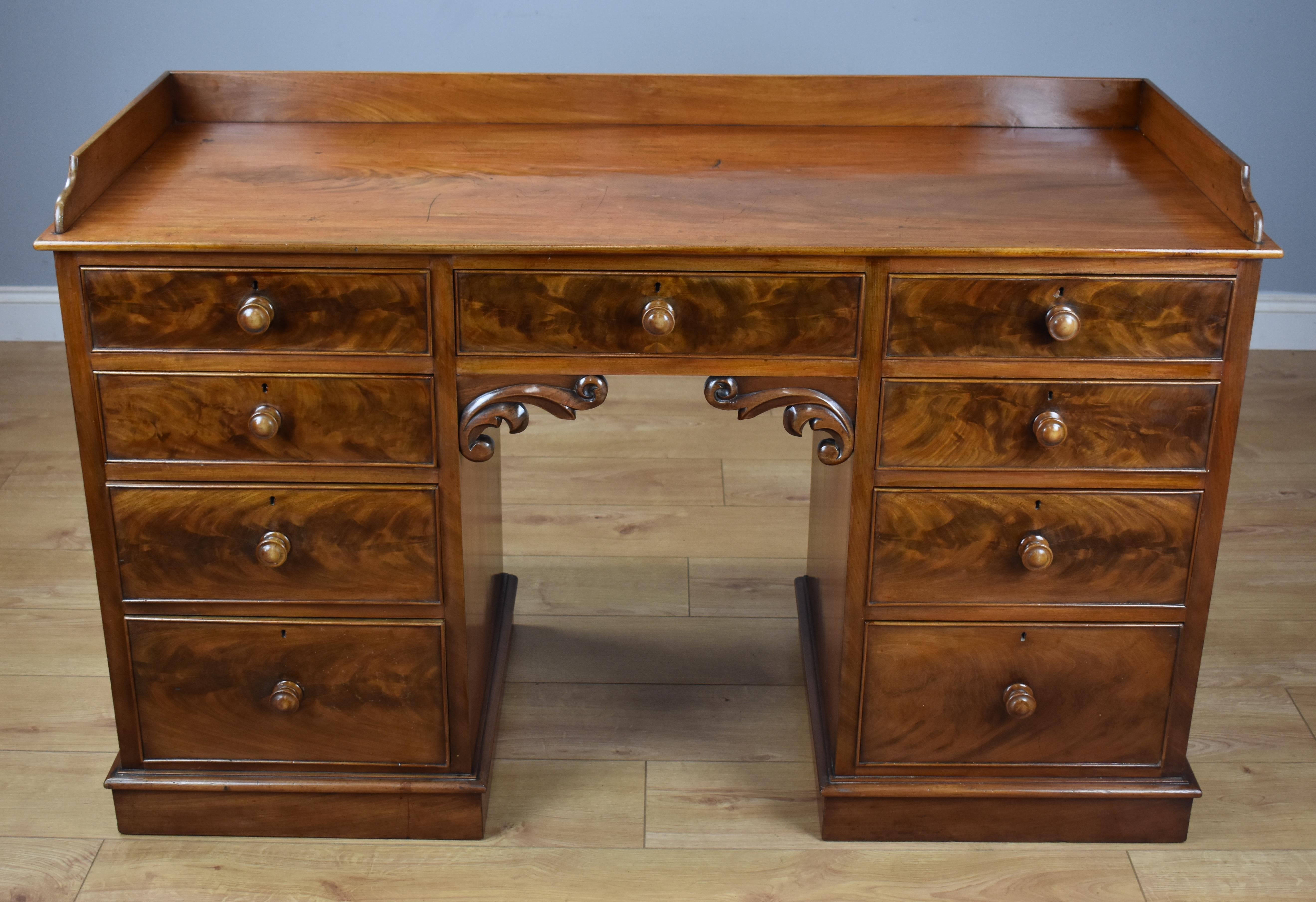 Victorian mahogany writing table in very nice condition with a gallery top over eight drawers with centre drawer over kneehole frieze with carved scrolled moldings. 

Dimensions: Width 53.5