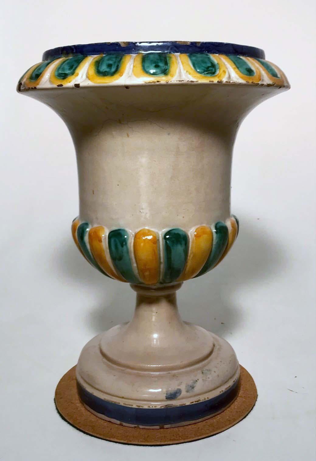 Diese Majolika-Urne ist aus Campana  Form, halb geriffelt in Senf und  smaragdgrün mit  geformter passender Rand. Es war für einen Blumentopf  ursprünglich, könnte aber auch einen stilvollen Weinkübel für ein Essen im Freien darstellen.
Dieses trägt