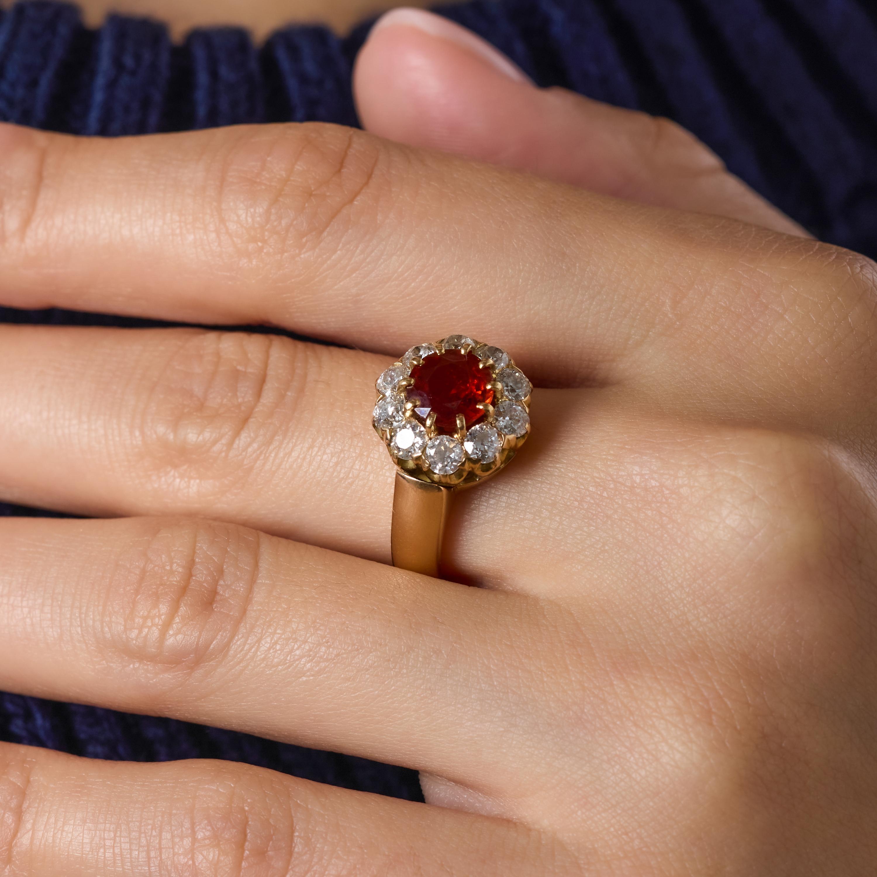 Questo radioso anello vittoriano è incentrato su un granato mandarino di colore arancione vivo, la cui tonalità luminosa attira immediatamente lo sguardo. Intorno, un'aureola di luminosi diamanti taglio Old European aggiunge profondità, fuoco e
