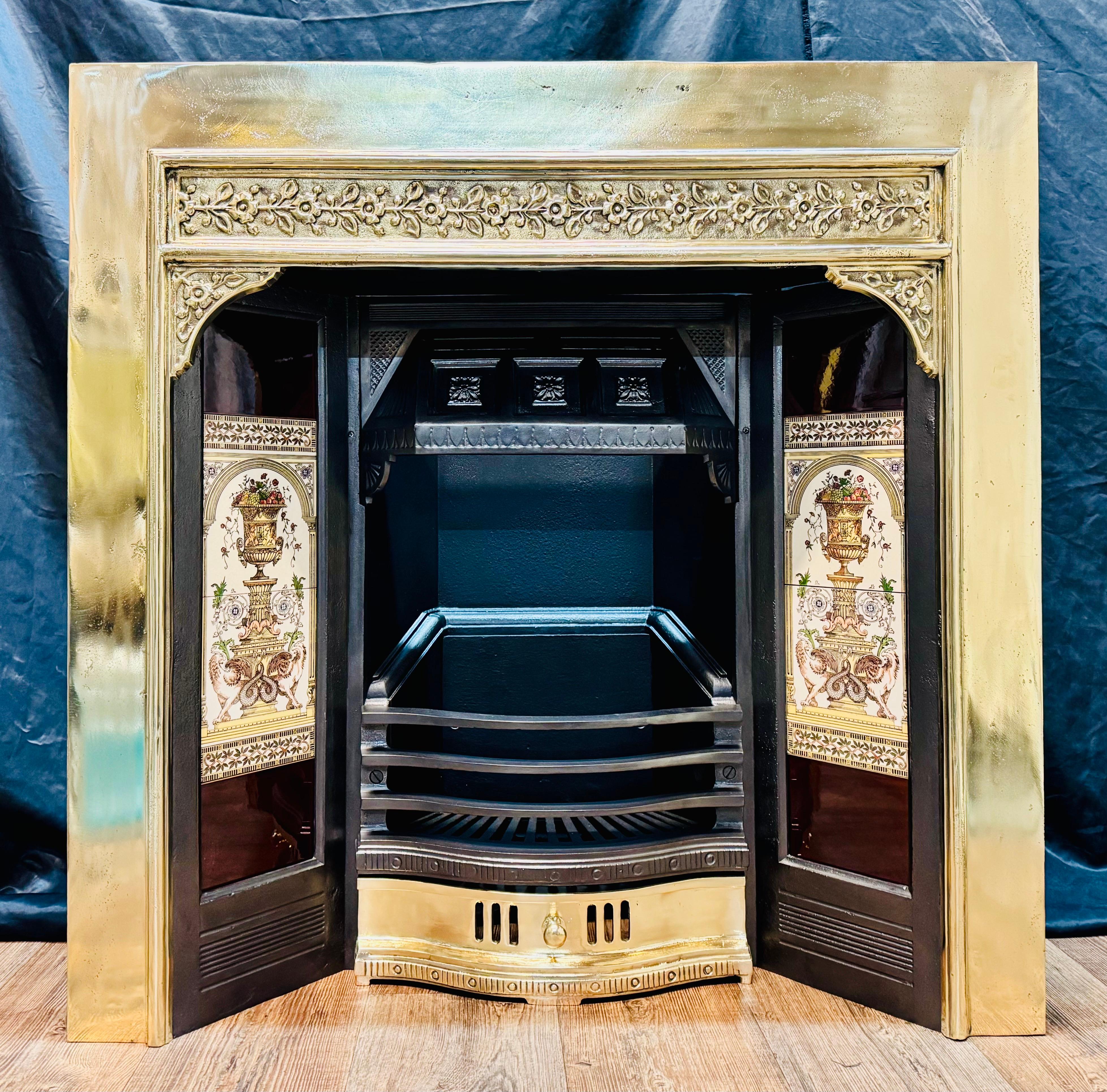 A substantial 19th Century Victorian manner polished brass fireplace insert. A fully polished brass outer frame displaying high relief horizontal tendrils set within a raised border. A set of tiles displaying large griffins at the base of an urn,