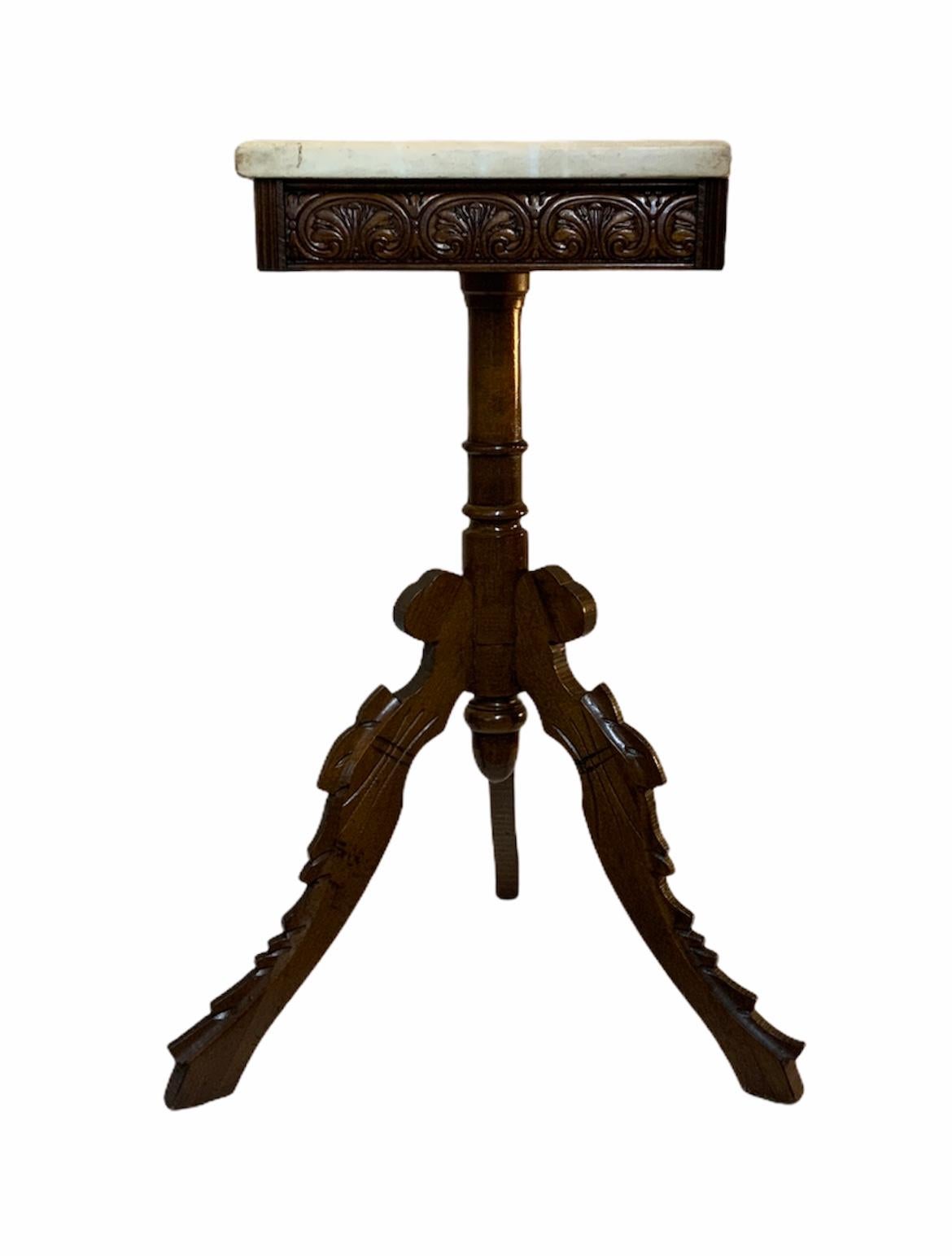 This is a charming tripod side table with a rectangular marble top. The upper wood base depicts a carving frieze with oval medals adorned in the center by 