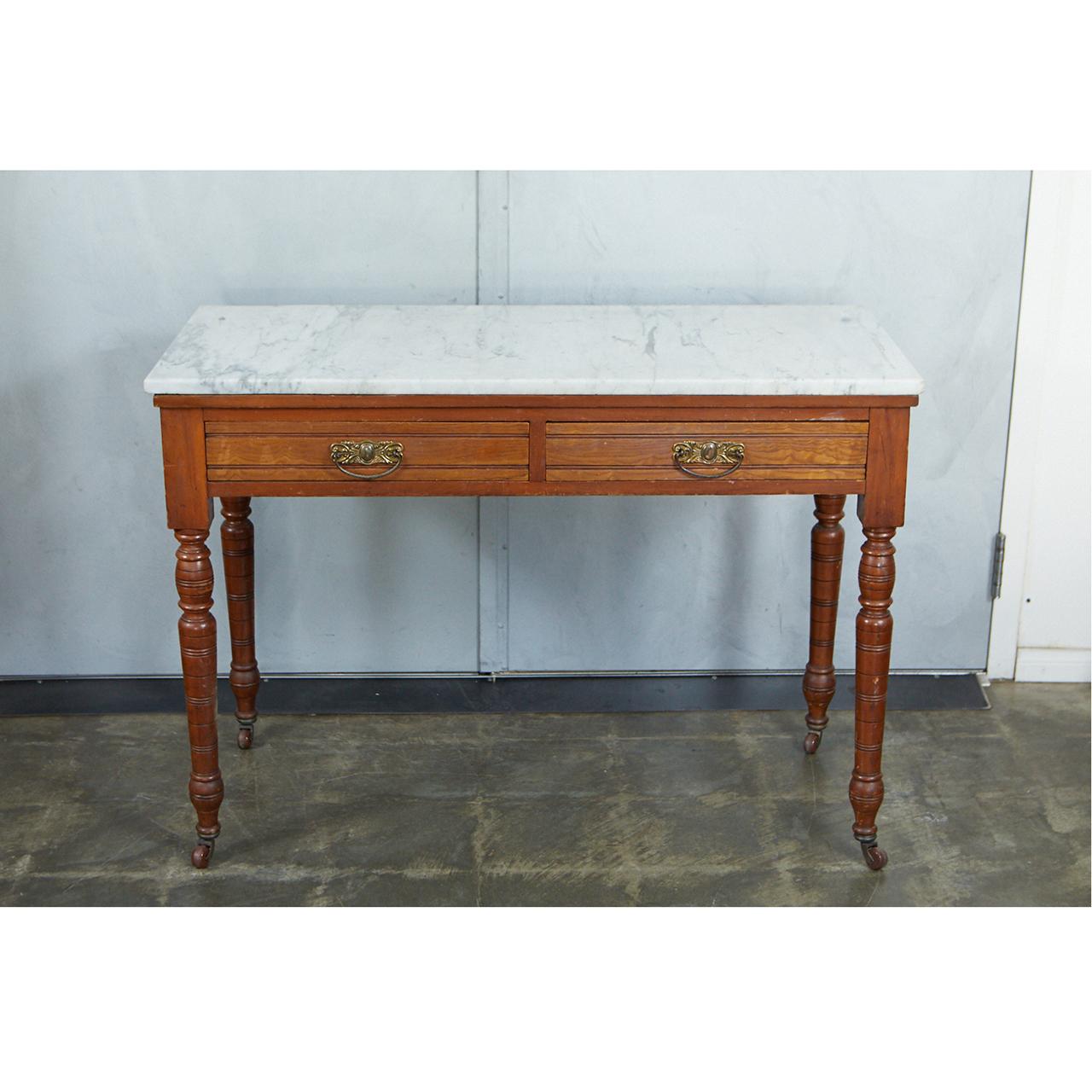A very nice English marble-top table from the 19th century, originally used as a washstand. The table has two-drawers with brass drop pull handles. This piece has nicely turned legs standing on casters. The diminutive size of this table makes it a