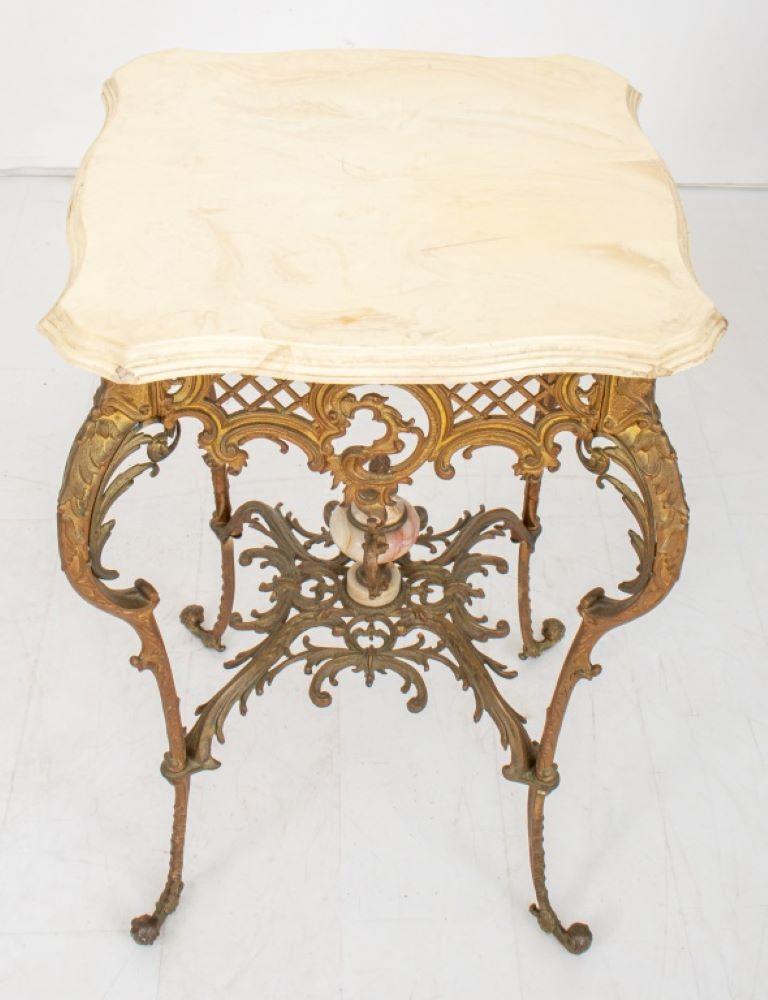 Table victorienne en métal doré surmontée de marbre, de style Rococo, avec un plateau rectangulaire en marbre Calacatta crème à bords moulés, sur une base en métal en forme de treillis et de rocaille et des pieds cabrolés joints par des brancards,