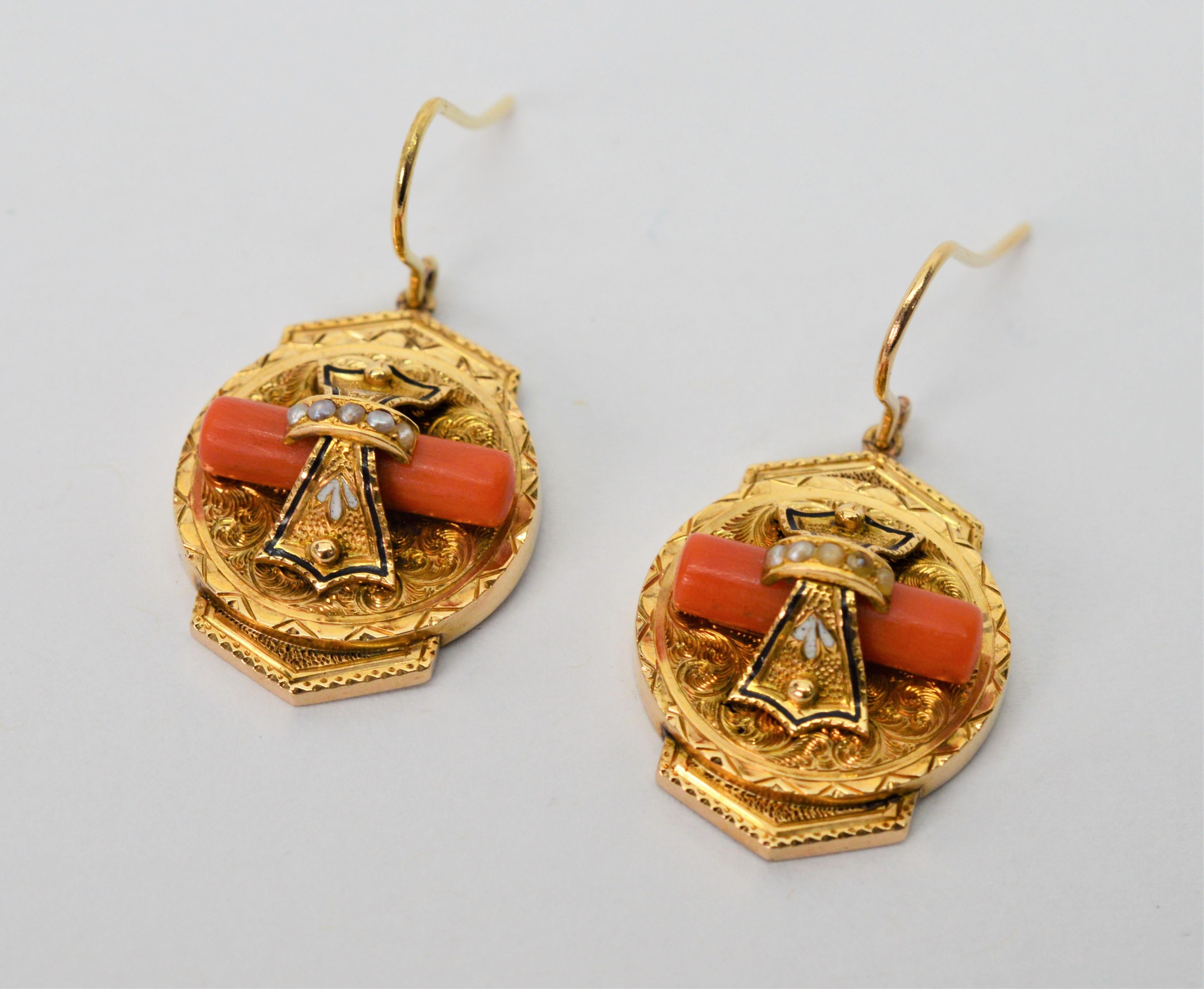 Natural coral, petite pearls and mother of pearl inlay adorn the facade of these ornately engraved medallion Victorian period earrings made of fourteen carat 14K yellow gold. Rare, three dimensional design and laden with artful eye-catching details,