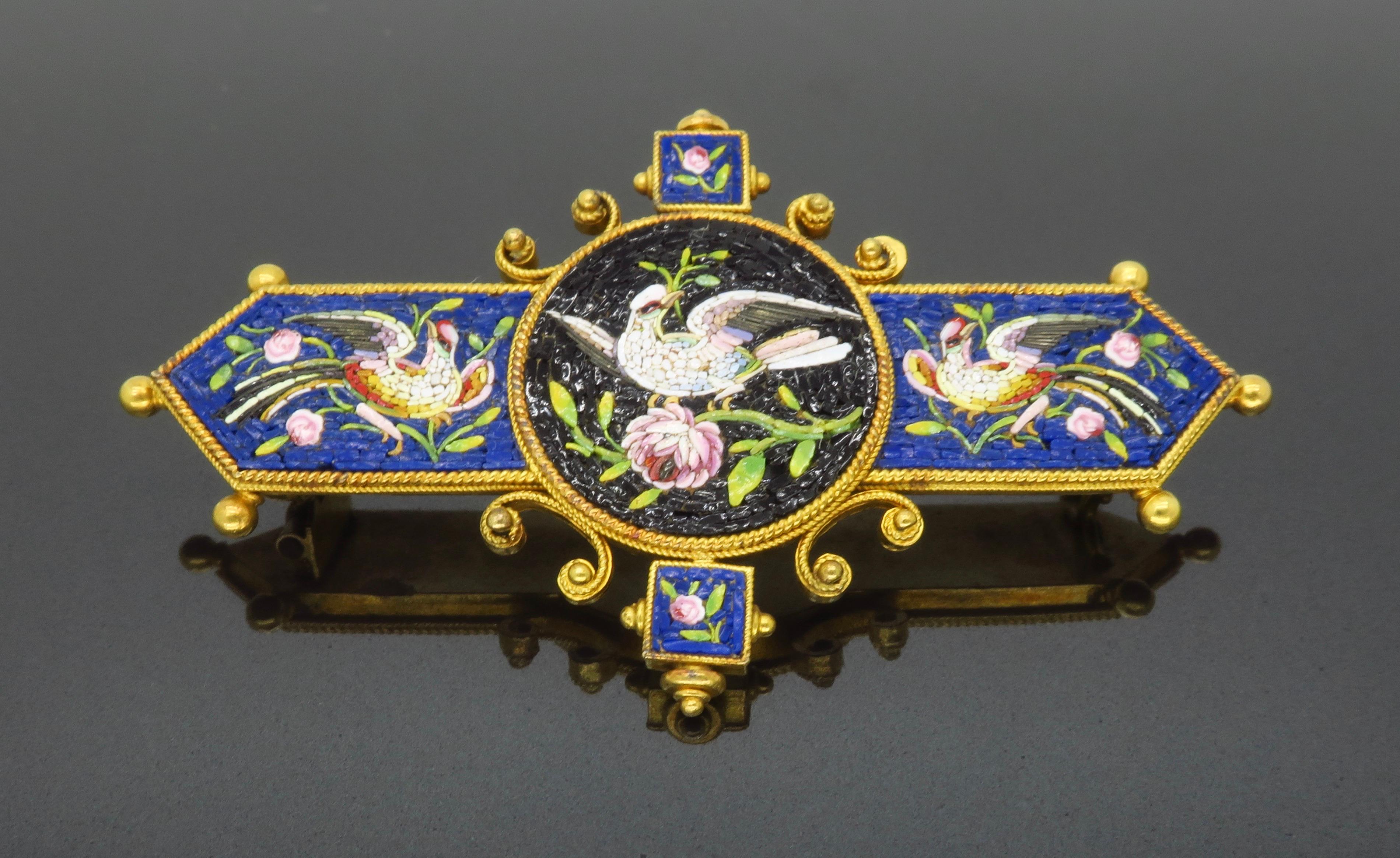 Exceptional Victorian Micro Mosaic brooch made in 18k yellow gold. The ornate detail captures three playful birds with blooming flower accents. This stunning design is created using tiny colorful stones comprised by hand to create the depth. The