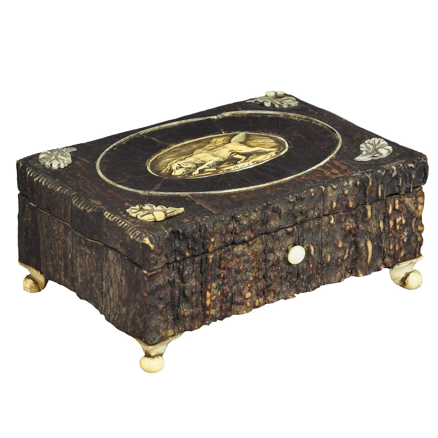 A marvelous antique rustic casket. It is made of wood, veneered with antler pieces. On top an antler plaque with staghound carving. The feet are made of antlers too. Executed ca. 1860. (veneer partly restored)

Measures: 
Width: 4.92