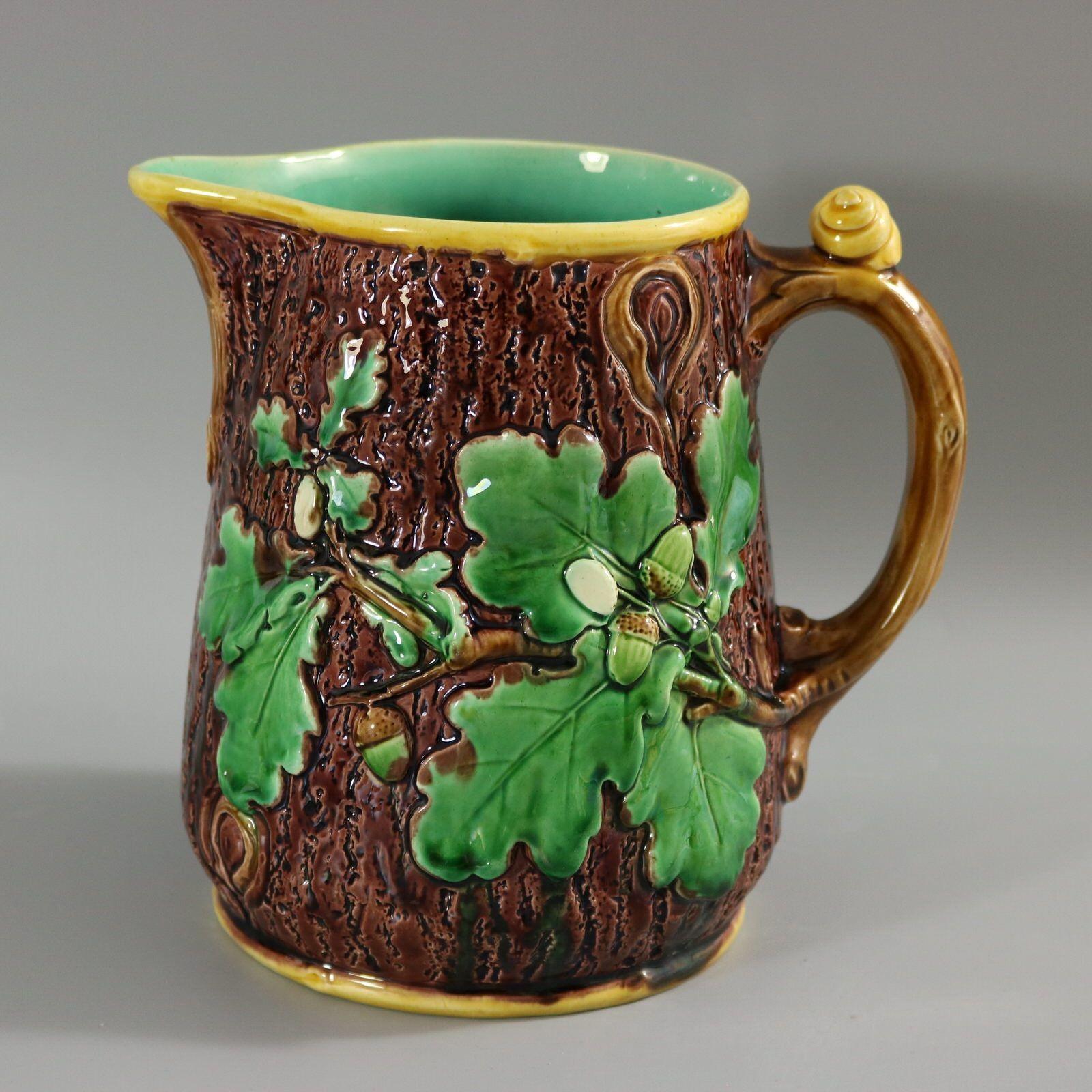 Minton Majolica jug/pitcher which features oak leaves and acorns to the sides and a snail to the handle. Colouration: brown, green, yellow, are predominant. The piece bears maker's marks for the Minton pottery. Bears a pattern number, '553'. Marks