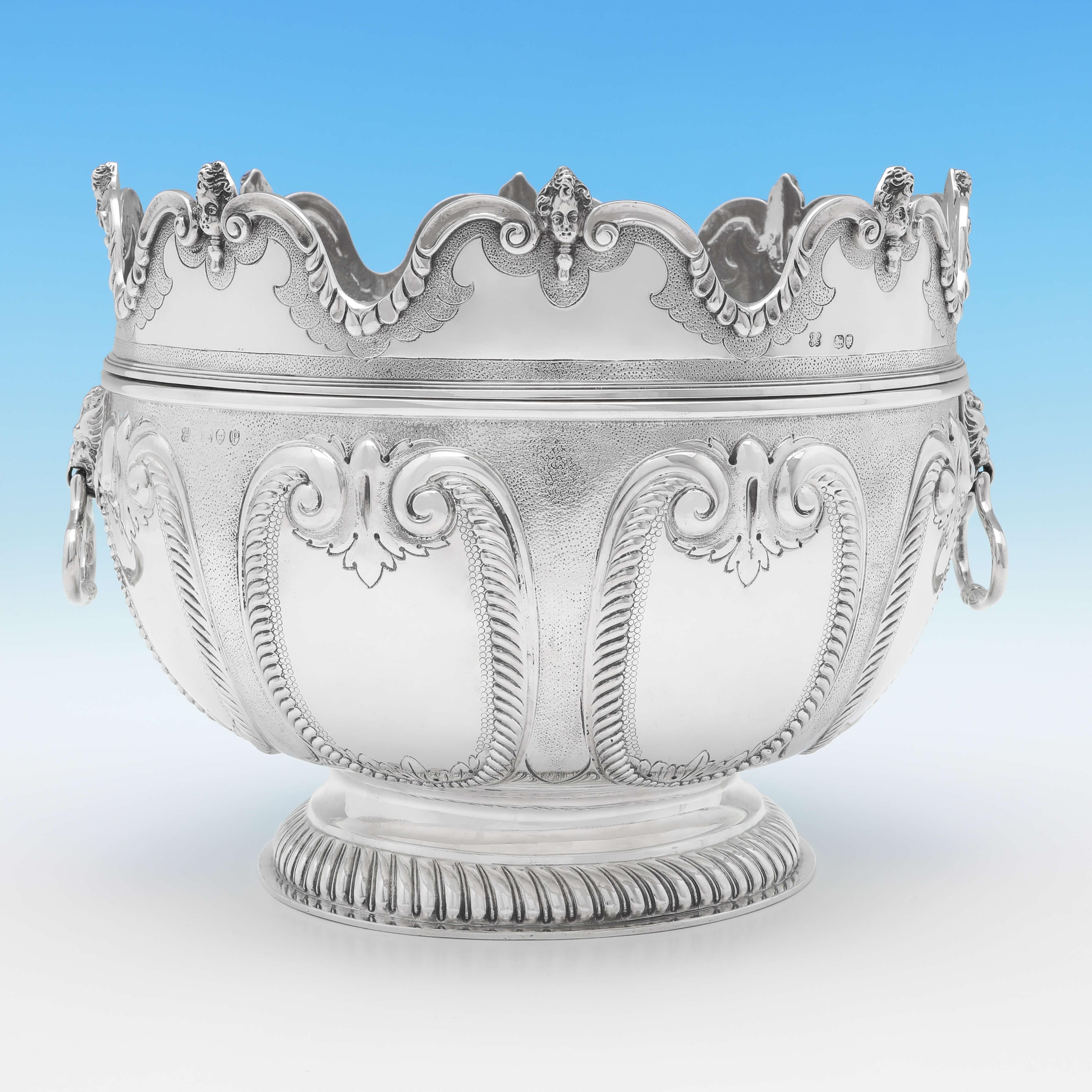 Hallmarked in London in 1890 by Aldwinckle & Slater, this striking, Victorian, antique sterling silver bowl, is in the 'Monteith' style, with a removable scalloped rim, lion mask drop ring handles, a fluted foot and chased decoration throughout. The