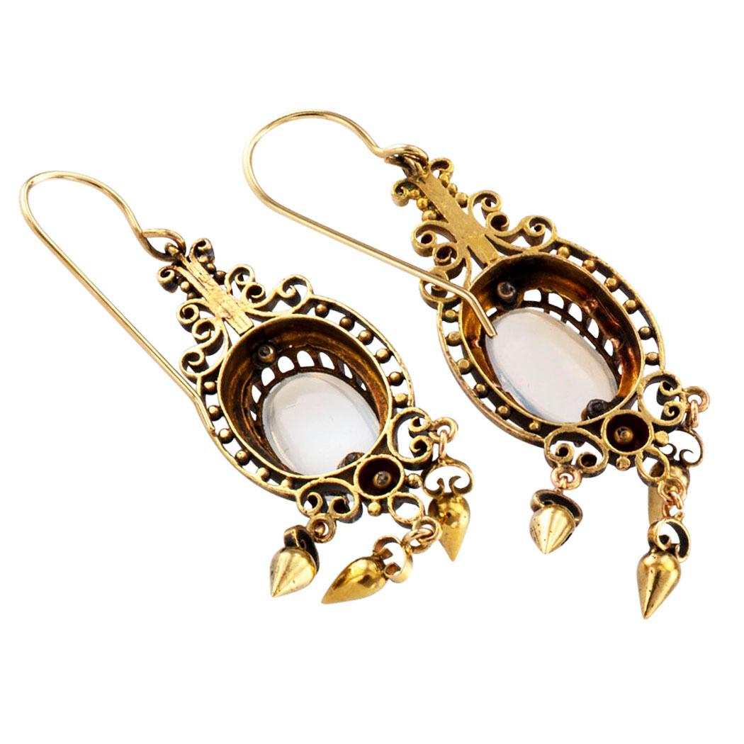 Victorian 1890s moonstone and gold pendent earrings. The articulated designs feature a pair of oval moonstones set in open work frames decorated with rounds beads and scrolling motifs, terminating with a fringe of teardrop-shaped beads and endowed
