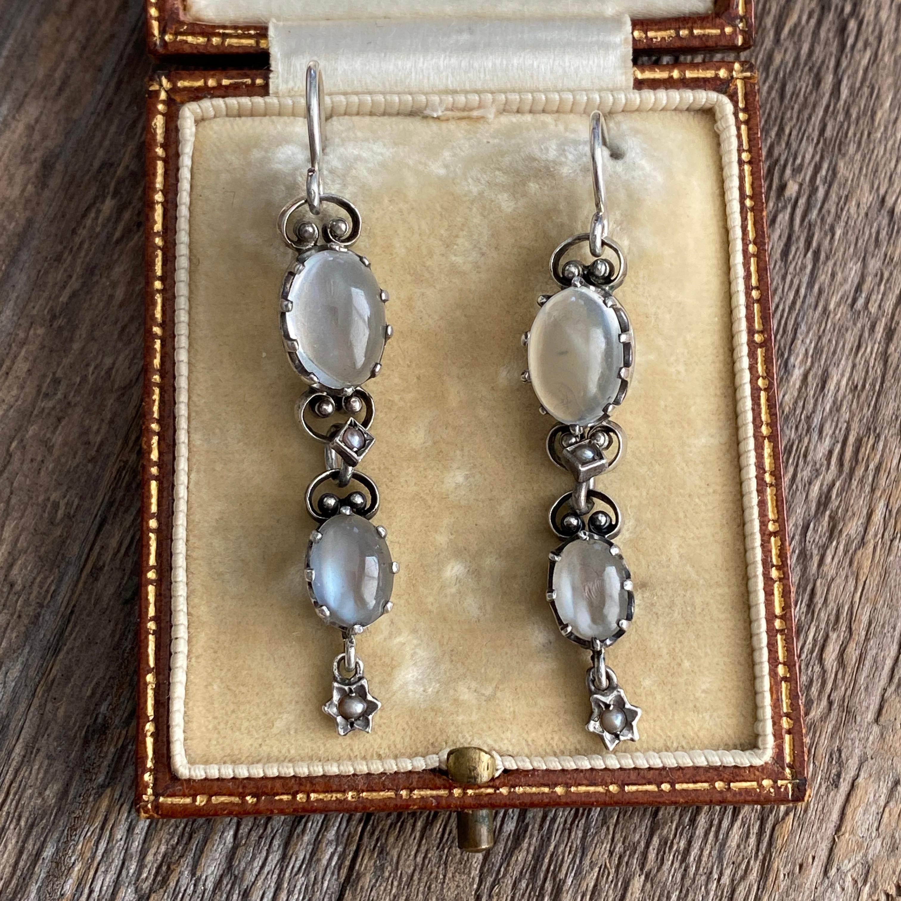 Details:
Lovely, ultra feminine cabochon moonstone and silver earrings from the Victorian Era. The moonstones are set in a dramatic claw style setting, with tiny seed pearl details in the links. The moonstone has a nice blue flare, and a beautiful