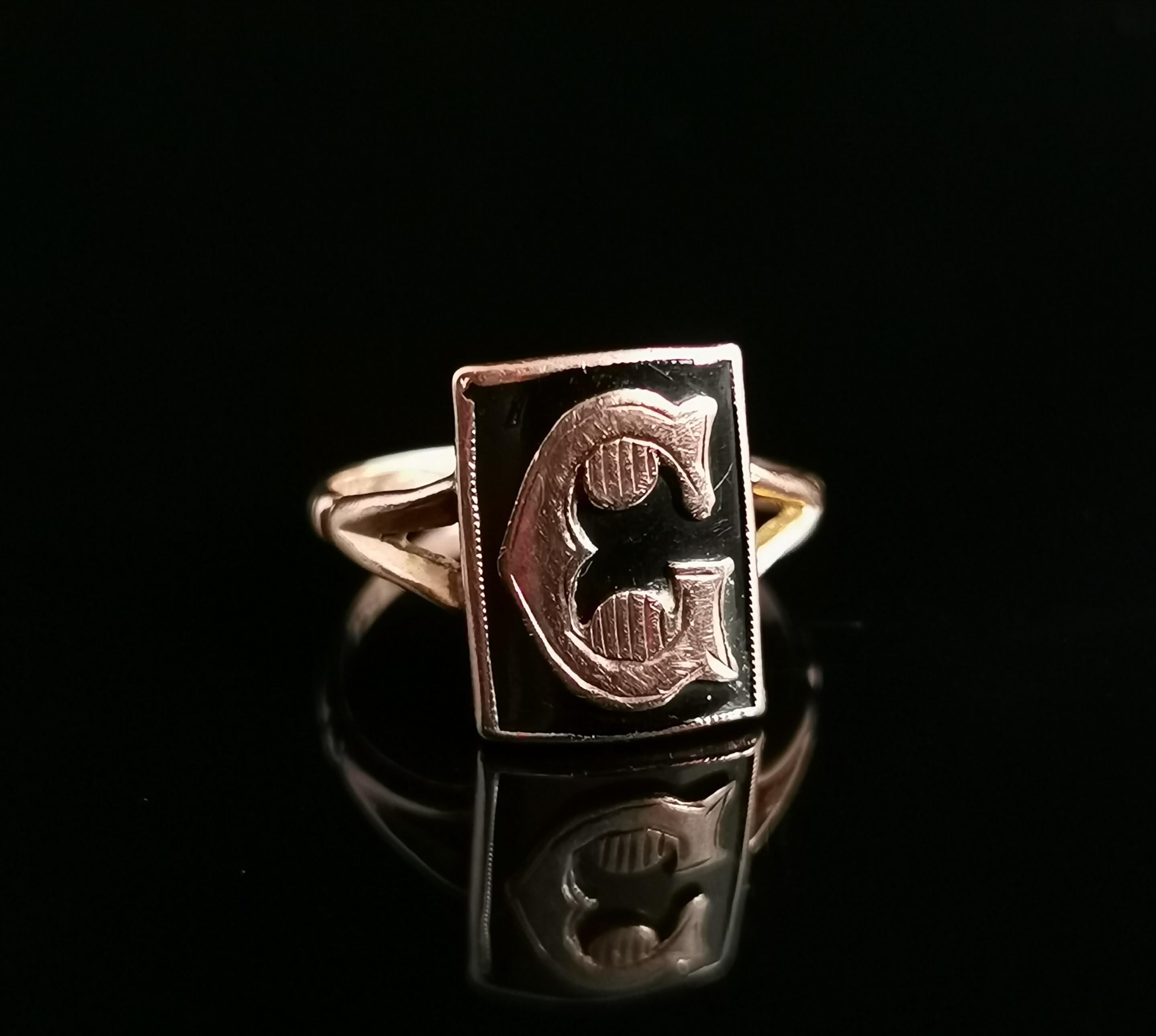 A pretty antique, late Victorian era mourning ring.

This is an initial ring with an applied rose gold letter C, lightly engraved and set on a rich black enamelled panel front.

The ring has decorative split shoulders and a slim smooth polished band