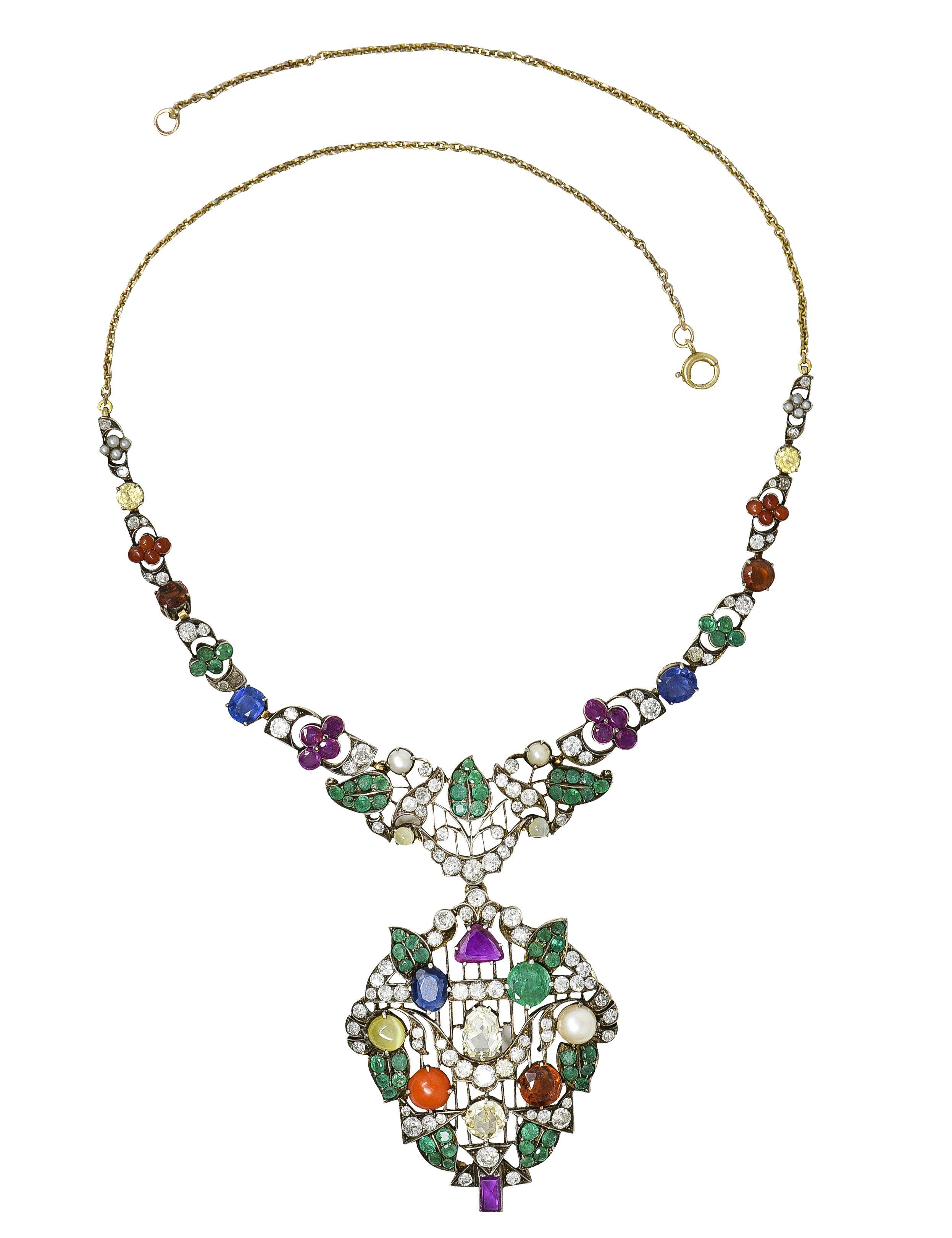 Necklace is designed as a garland style necklace with knife edge striation, scrolling foliate, and clustered gemstones. Leaves are set with round cut emeralds weighing approximately 3.55 carats total - translucent bluish green. With clustered round