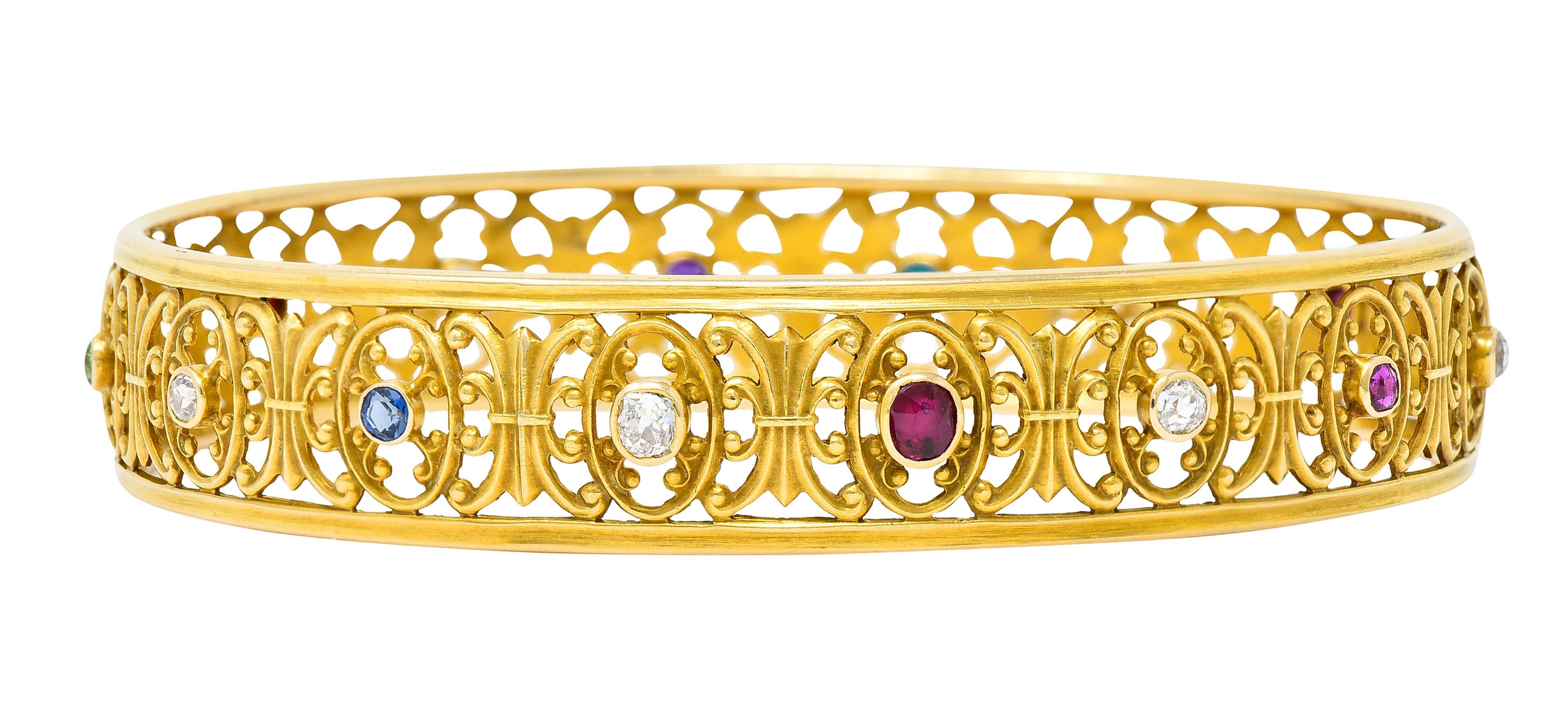 Bangle bracelet is decoratively pierced with scrolling flourishes and cartouches. With bezel set gemstones fully around - citrine, demantoid garnet, amethyst, turquoise, and opal. While featuring sapphires, rubies, and diamonds weighing collectively