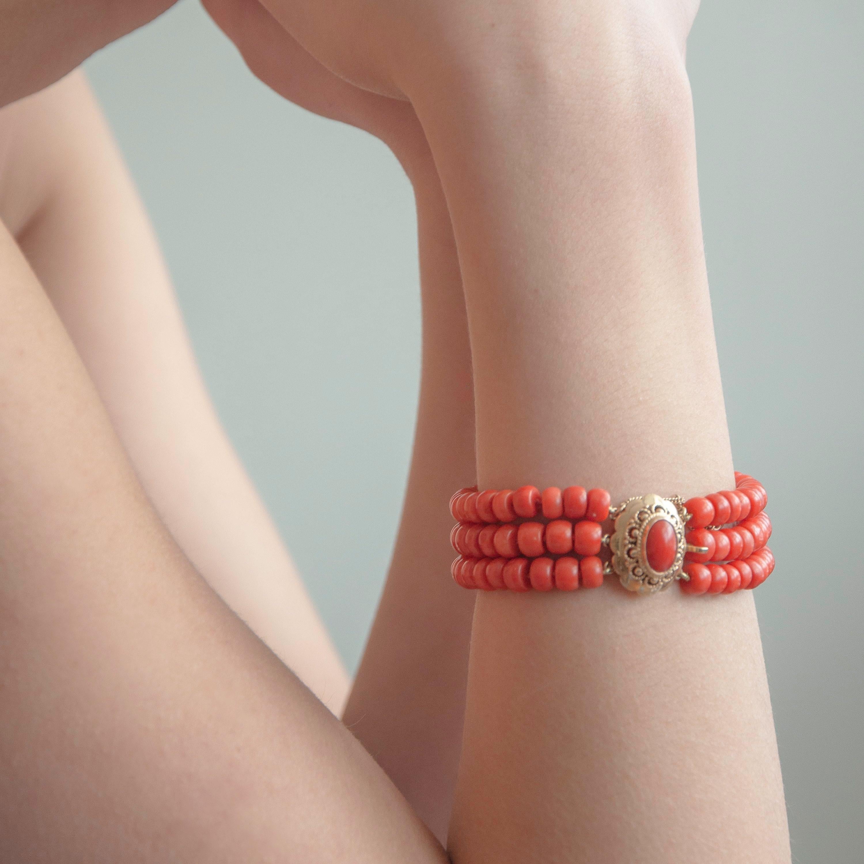 A natural red coral multi-strand beaded bracelet made with a 14 karat gold cannetille clasp. The bracelet has barrel-shaped beads with a diameter of approximately 6 millimeters each, which are in great condition. The cannetille work clasp is