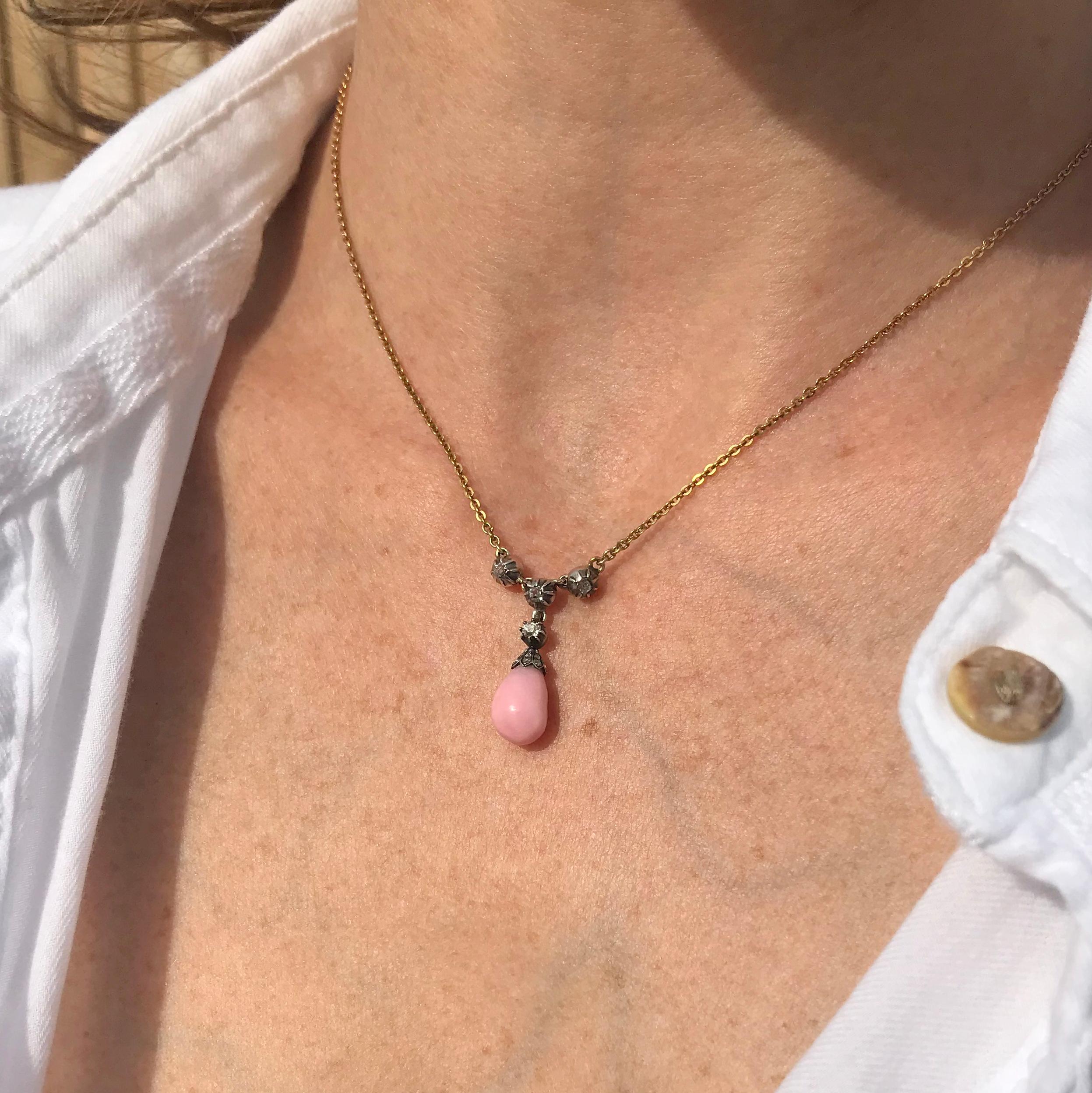 Antique jewellery at it most creative and beautiful. The conch pearl (certified as natural) displays a stunning, soft pink and is held in a stunning silver cup set with fifteen rose cut diamonds in five graduating lines. Four old cut diamonds are