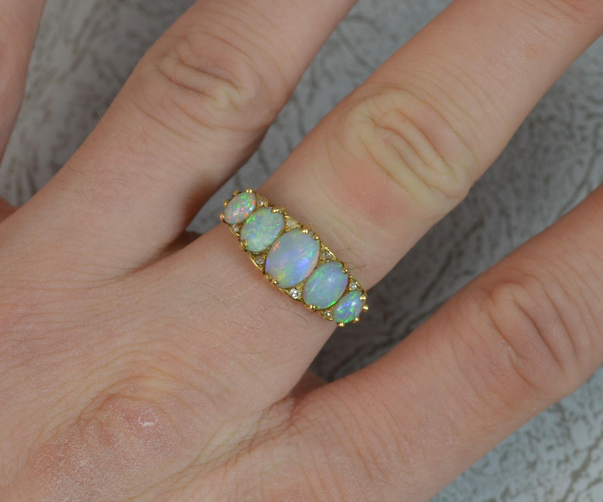 A beautiful true Victorian period cluster stack ring c1880.
SIZE ; N 1/2 UK, 7 US
Solid 18 carat yellow gold example with small diamond accents in between.
Five natural oval shaped opals of slightly graduated size with pierced floral setting above