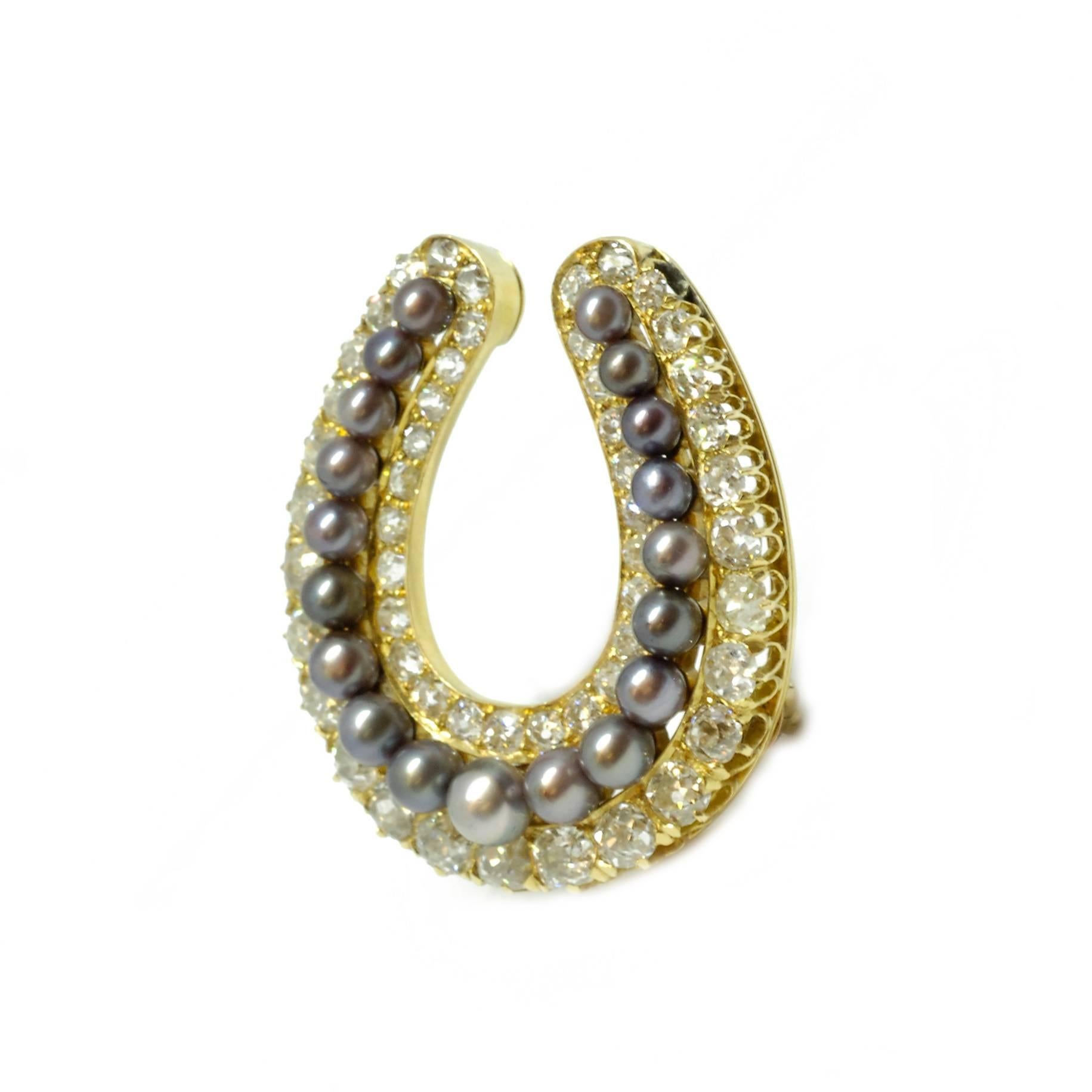 A Victorian brooch in the form of a horseshoe. Set with graduating natural Oriental black pearls, bordered by a row of old cut diamonds and mounted in 18ct yellow gold and silver. The brooch fitting is detachable and there is a fold down pendant