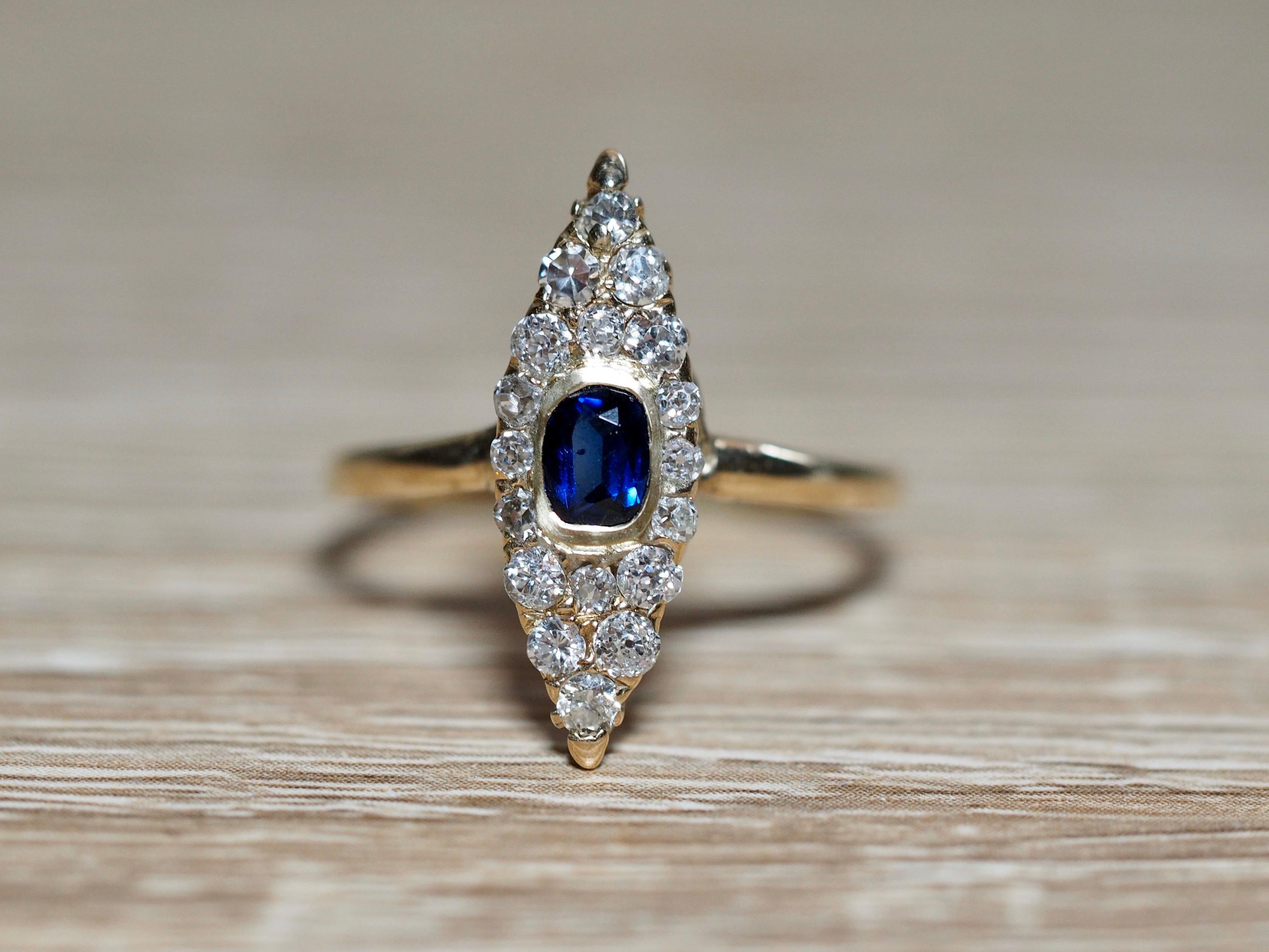 This Victorian Navette ring dates back to the early 1900's. The center is a deep royal 0.35 carat blue sapphire center illuminating in color. It is bezel set in a yellow gold frame sitting flush on the ring. The center is surrounded in the famous