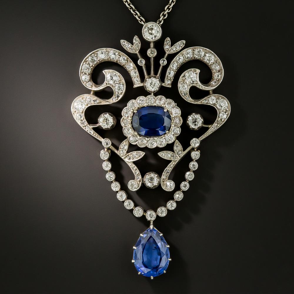 This resplendent rarity, hand fabricated in silver over gold toward the latter-19th century, features a pair of velvety royal blue gemstones: a central faceted oval  sapphire, weighing 3.20 carats, and a pear shape drop sapphire weighing 6.40 carats