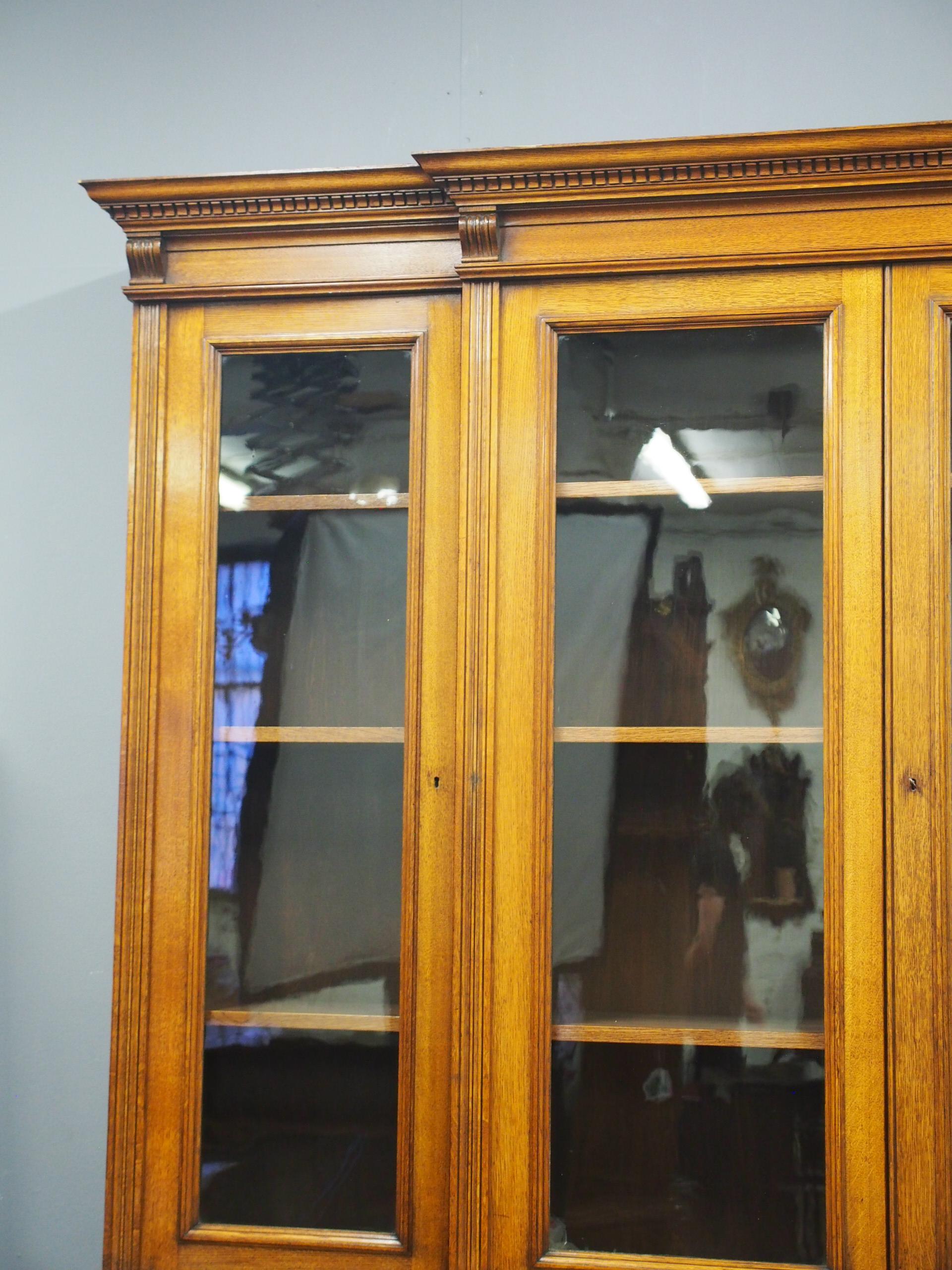 Late Victorian oak 4 door breakfront bookcase, circa 1870. The top has a dentil detailed cornice with stylish moulding, and 4 small corbels beneath. Behind the glazed doors in the top section are 3 polished, adjustable shelves, with solid oak