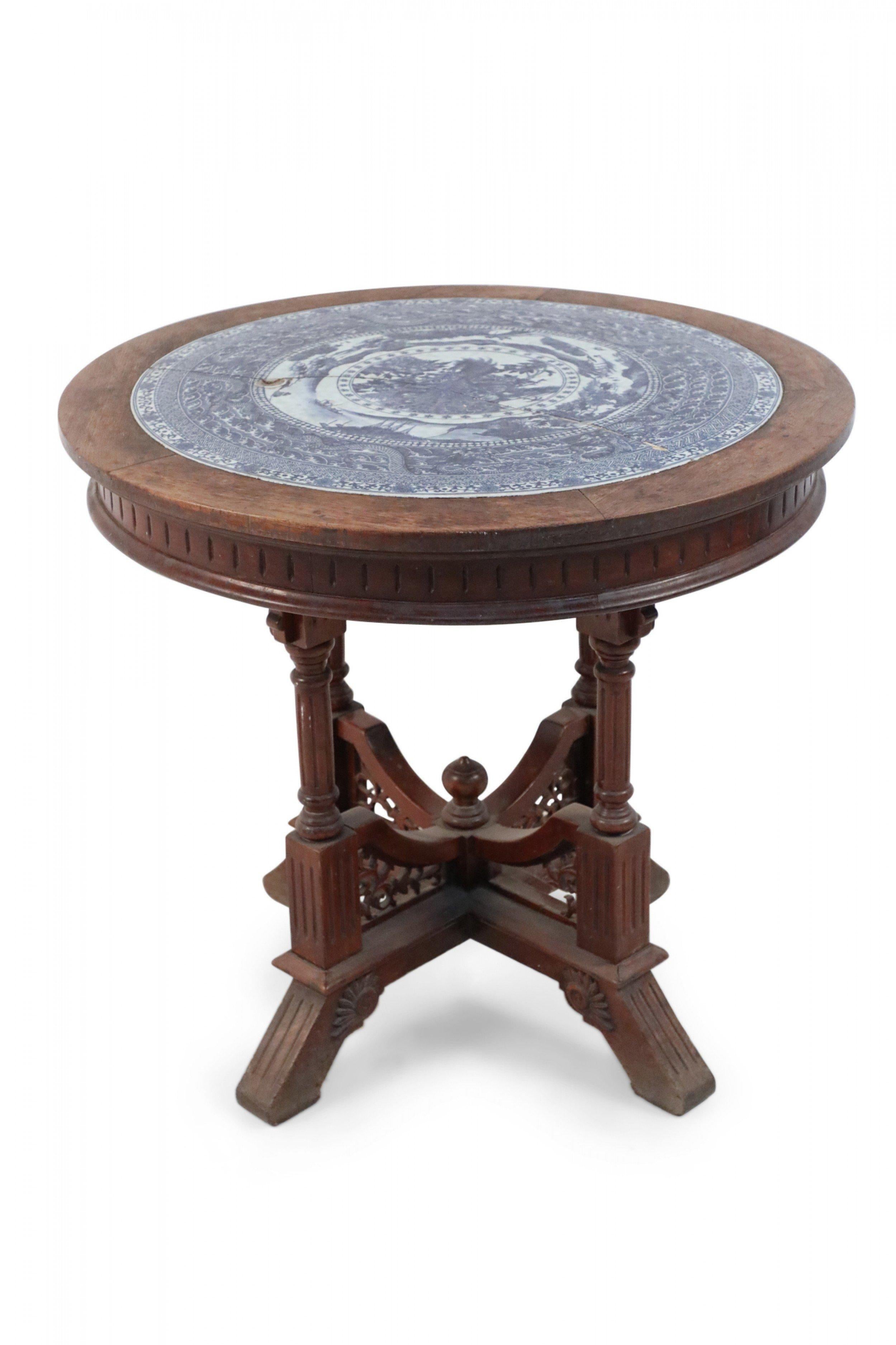 Victorian Aestheticism-style round oak center table having an inset antique, 18th century blue and white porcelain plate (as is) decorated in alternating bands of circular patterns and traditional motifs, atop an incised apron supported on four