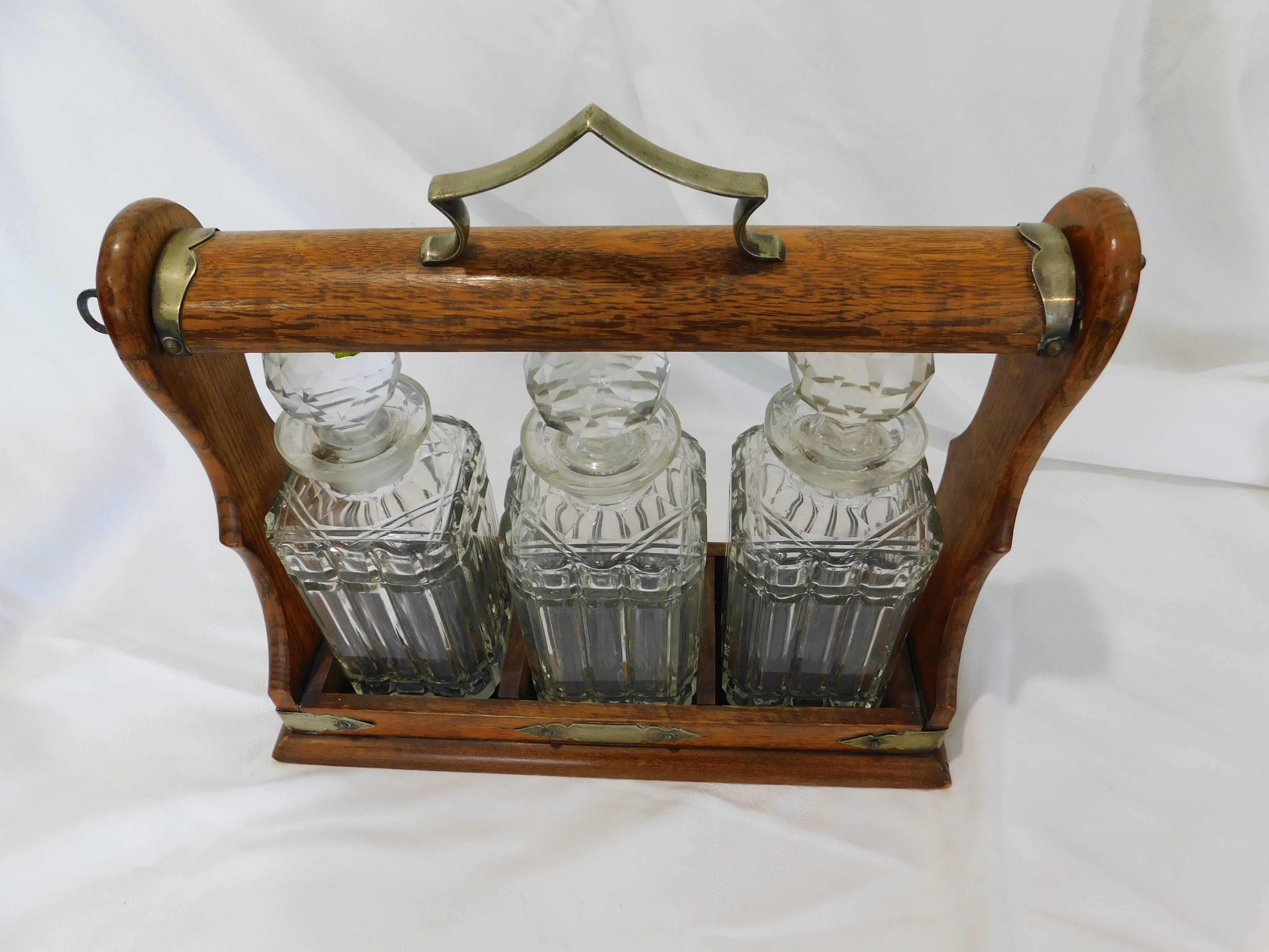 Original antique Victorian oak and silver metal tantalus with three crystal decanters. Comes with key to lock in the liquor or wine decanters.