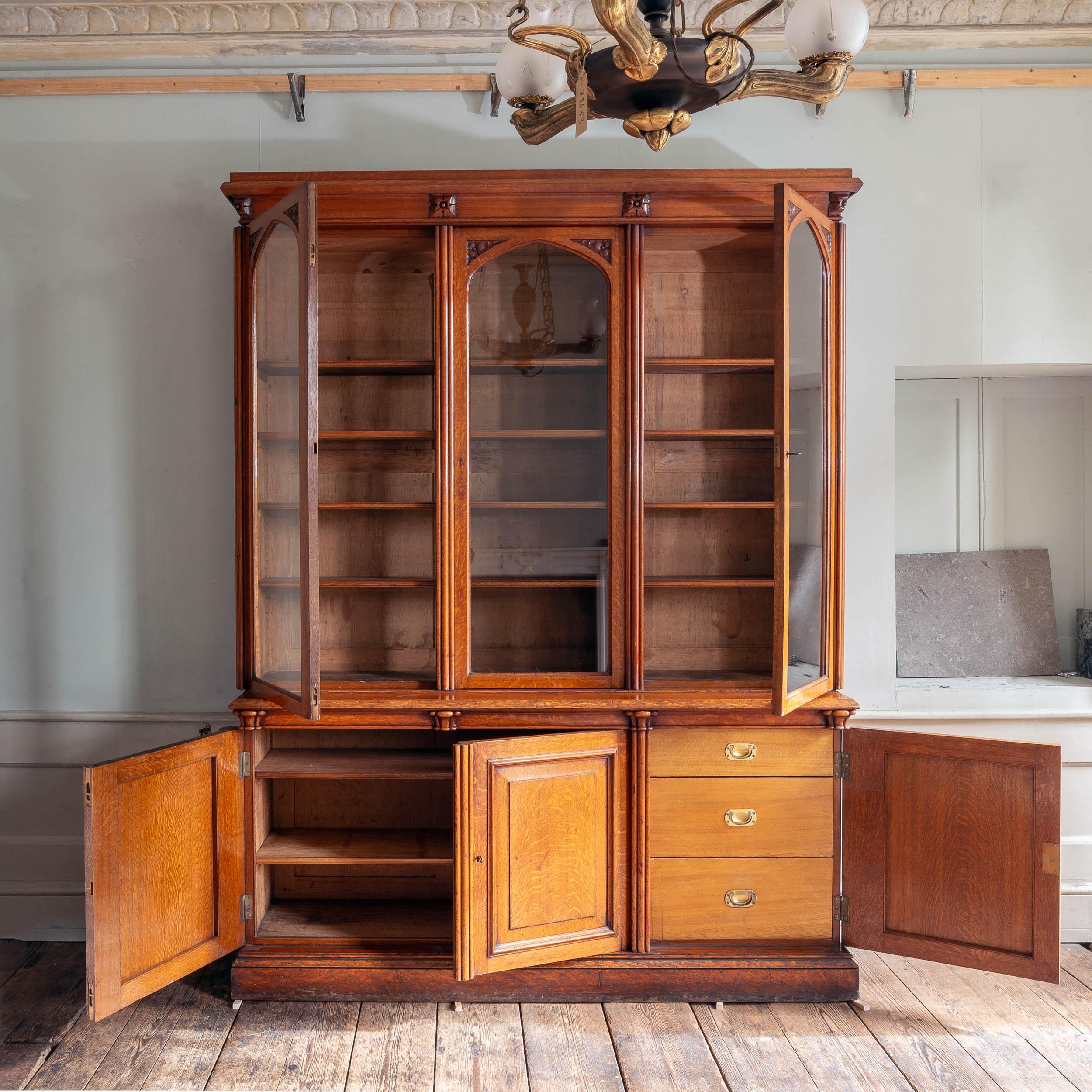 Una libreria vittoriana in Oak, del 1850 circa, con cornici intagliate a fogliame su ciascuna delle porte vetrate ad arco, l'interno con scaffali regolabili, la base con porte a pannelli rialzati e campiti, il tutto intersecato da pilastri a