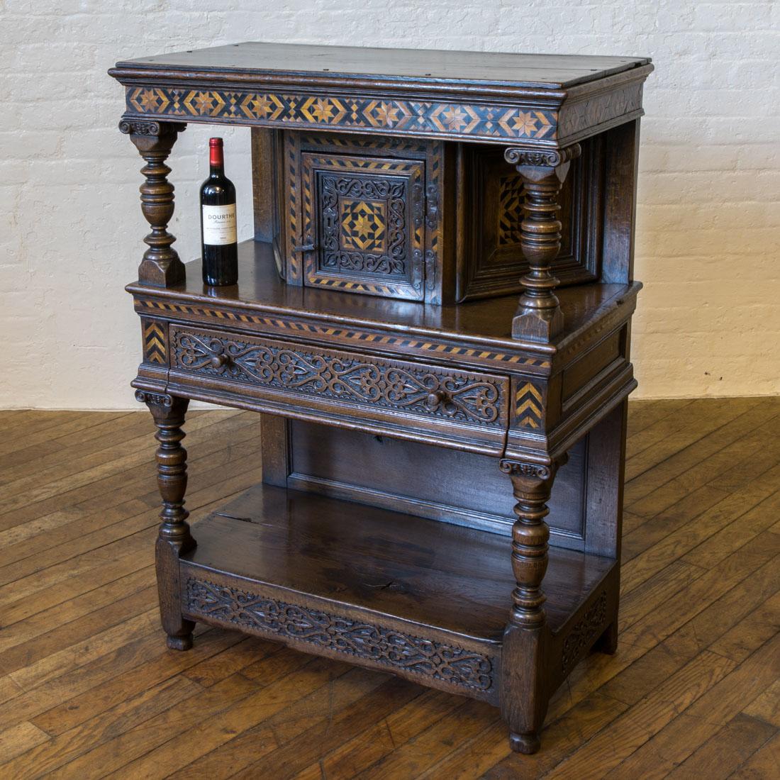 A small and very attractive solid oak court cupboard set throughout with carved and geometric inlaid detail made in the late Victorian period as a copy of a mid-17th century design. With odd marks and splits as you could expect, but in generally