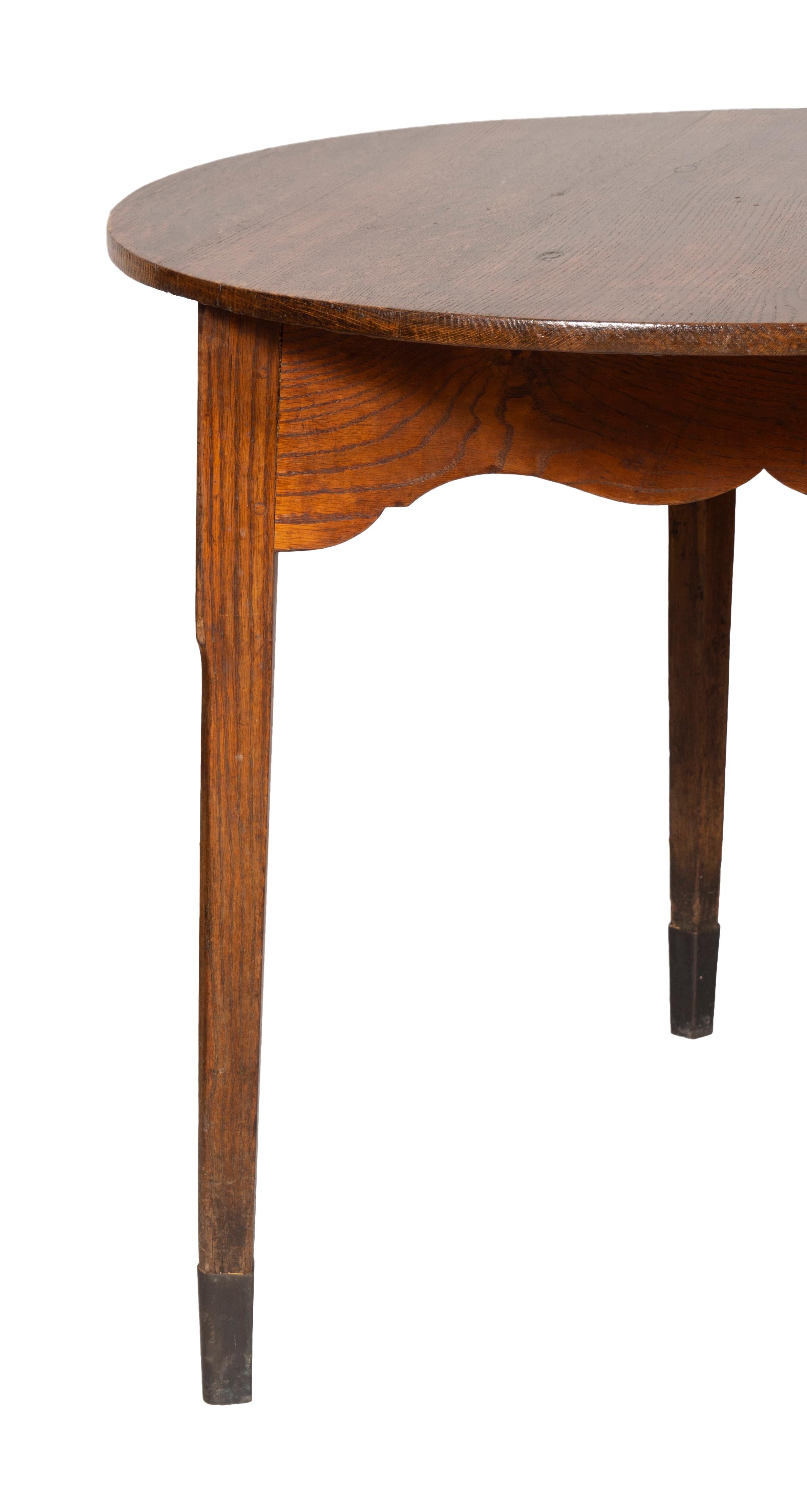Circular top and raised on three tapered square legs with oxidized brass feet.