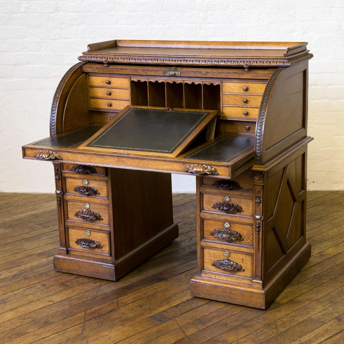 A stunning Victorian solid oak cylinder desk of outstanding workmanship and design. The galleried top gives way to a finely carved cylinder front, that reveals a well fitted interior with a newly leathered writing surface of which the central