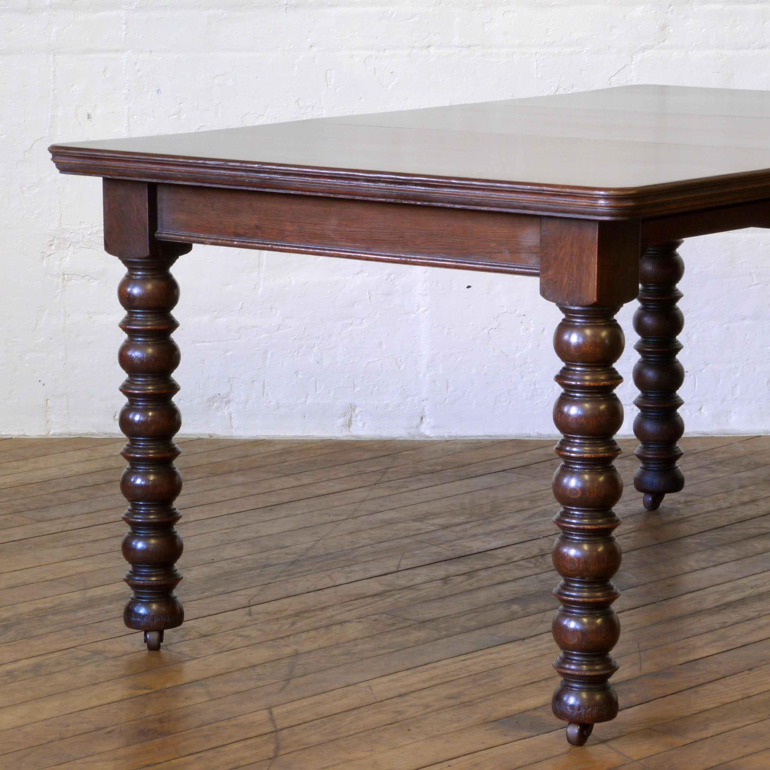 An attractive solid oak dining table. Perfect for six chairs when extended and four when closed. The bobbin legs are crisply turned and still retain their original castors. The winding mechanism allows you to take out the leaf and close the table