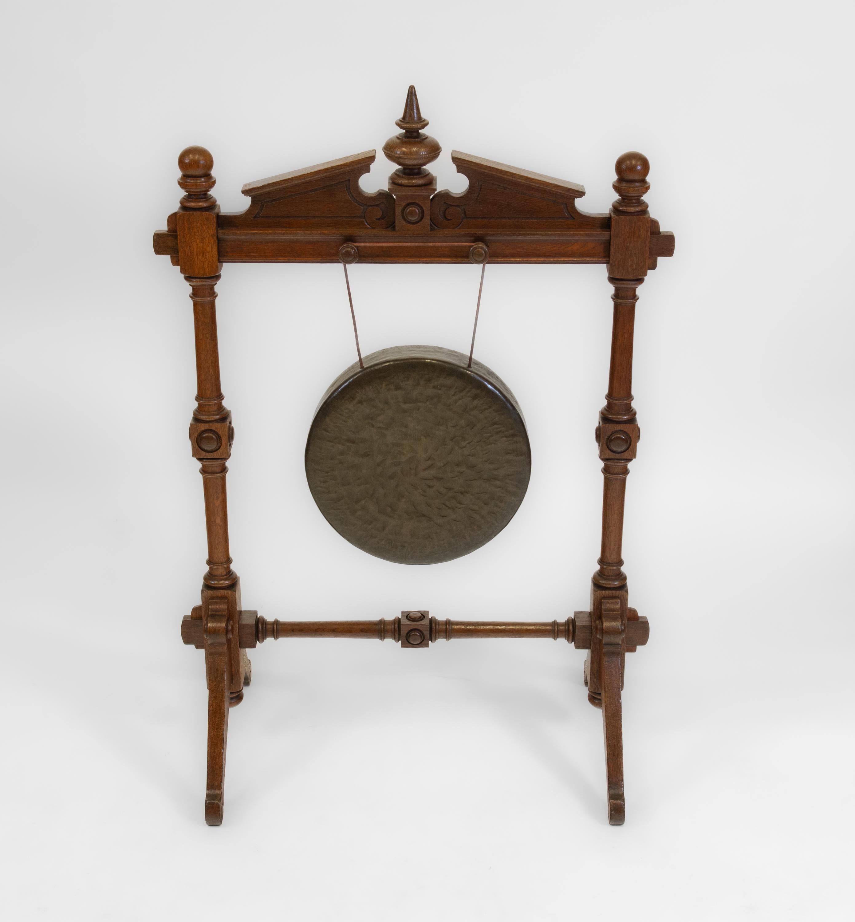  Gong de table et percuteur en chêne du XIXe siècle, datant de la période du Mouvement esthétique. Anglais - Circa 1870.

Le cadre du gong est en chêne massif. Le fronton est fixé aux supports tournés par des chevilles. Le gong repose sur des pieds