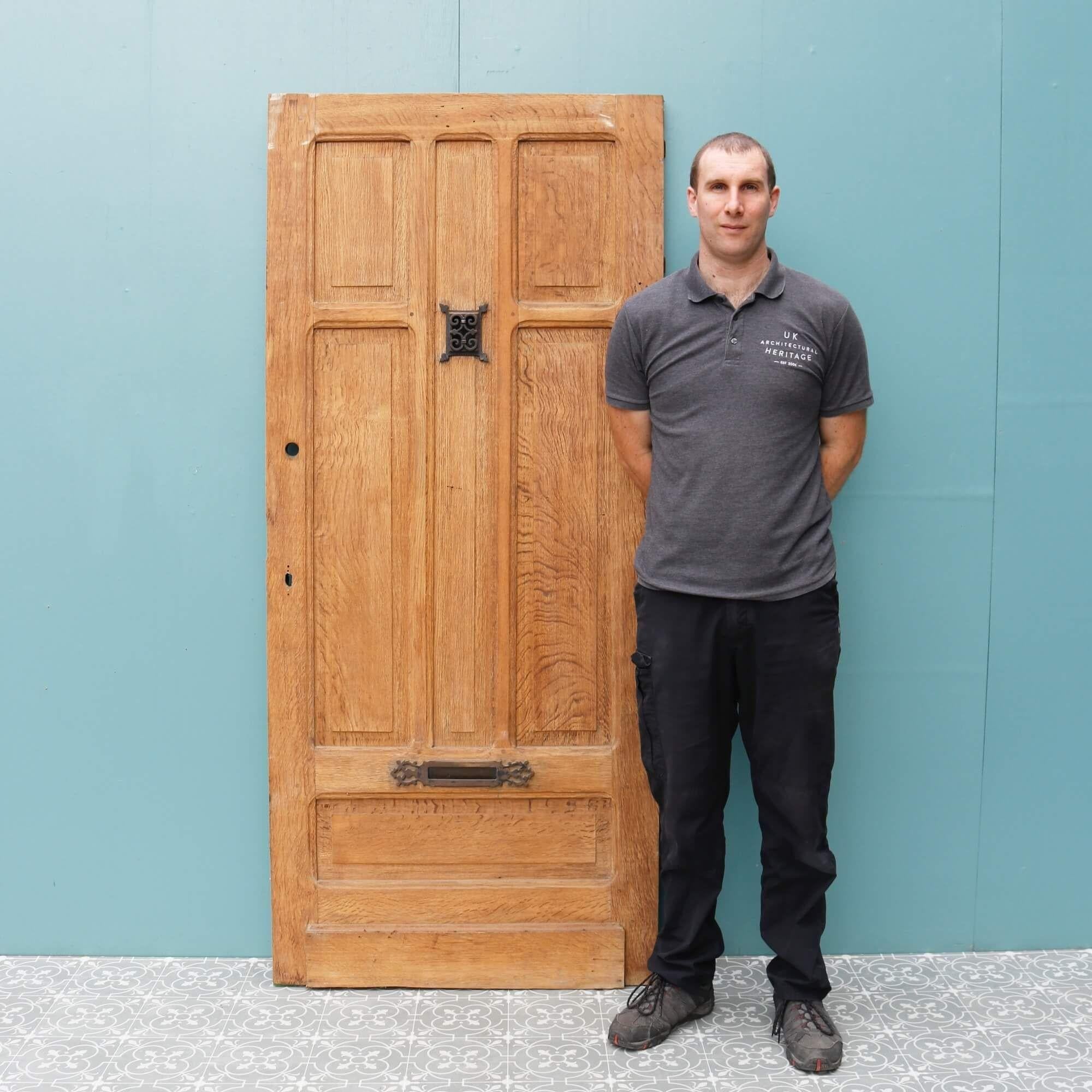 An antique Victorian oak front door with an original wrought iron letterbox and peephole originating from early 20th century France. The warm colour and bare wood finish of this antique oak door gives it a timeless appearance that would make a