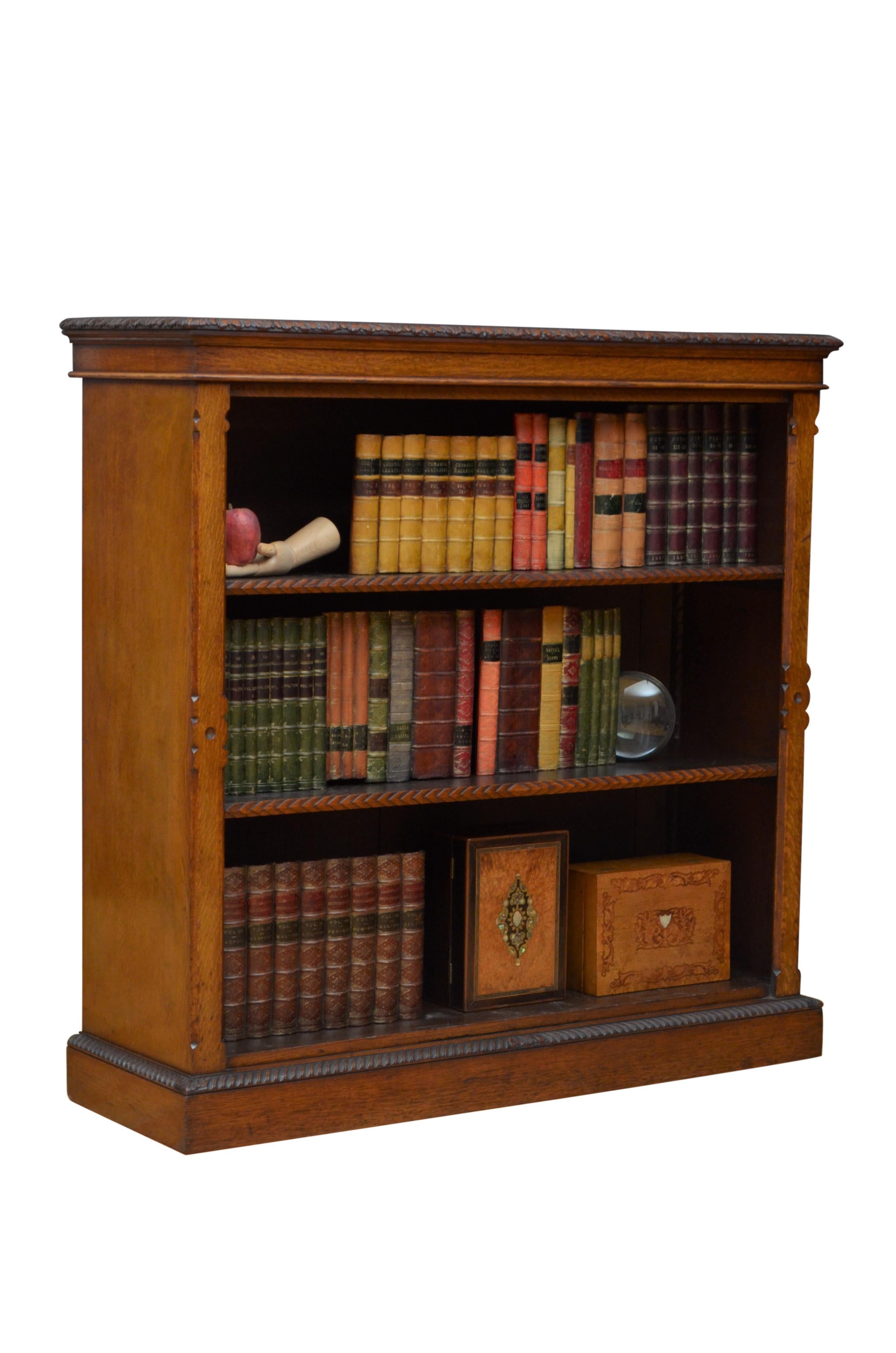  A quality Victorian open bookcase in solid oak, having attractive top with finely carved edge above two height adjustable shelves also with carved edge, flanked by decorative, canted pilasters, all standing on carved plinth base. This antique